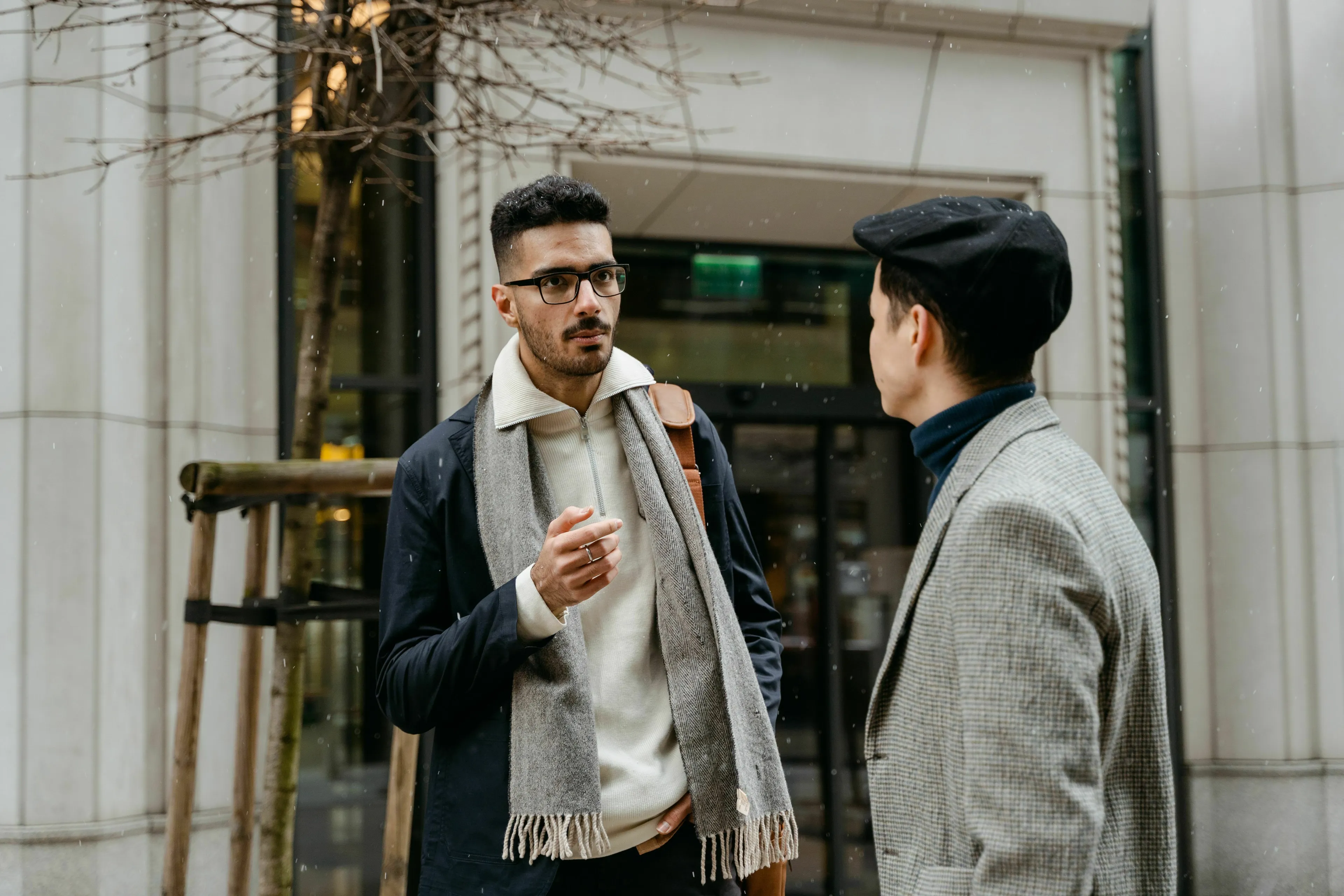 Uncover your stress response type: two men, one in glasses and a scarf, talk on a city street.