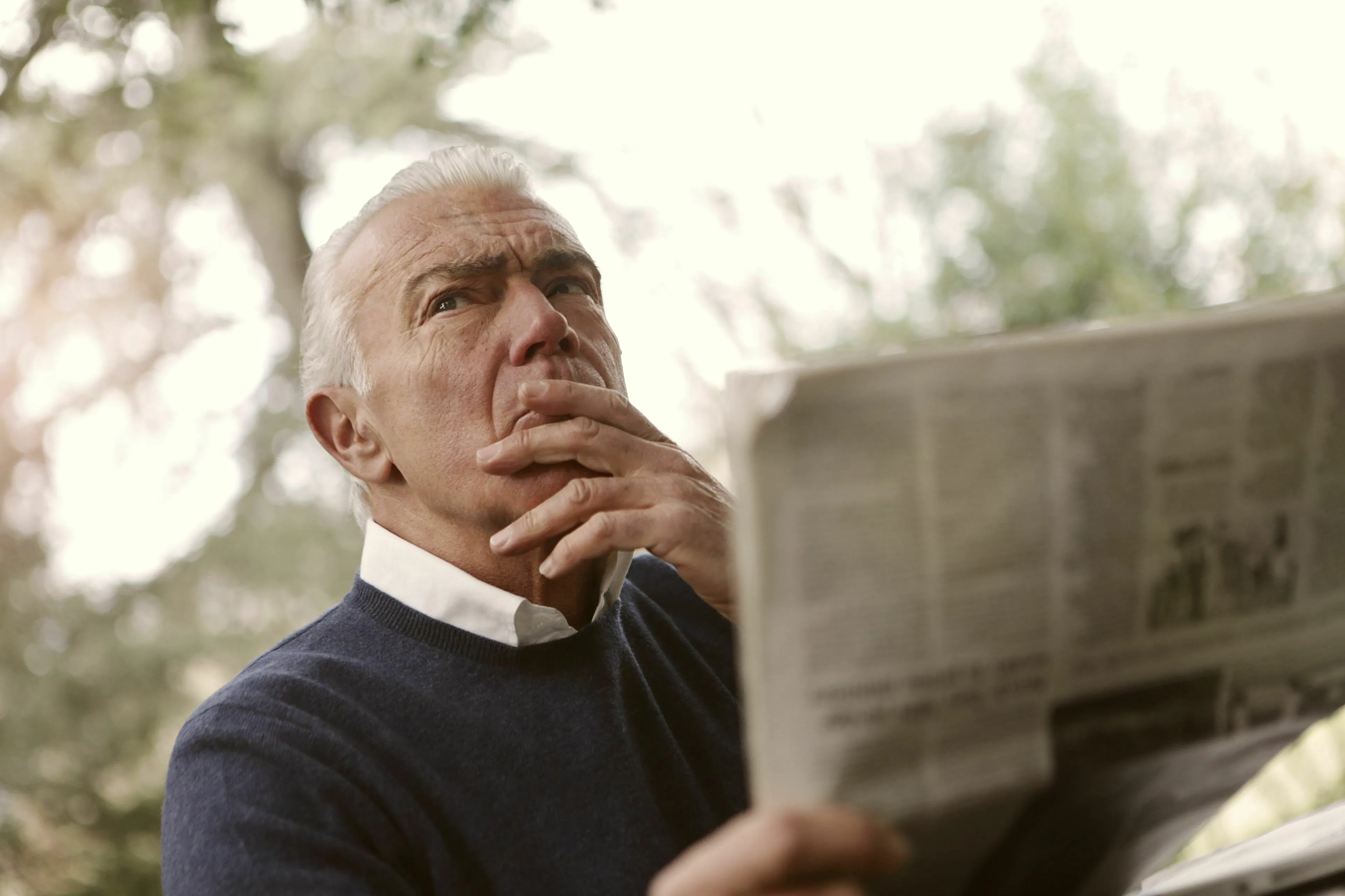 A man reads a newspaper, looking stressed and contemplating bad news, revealing his stress response type.