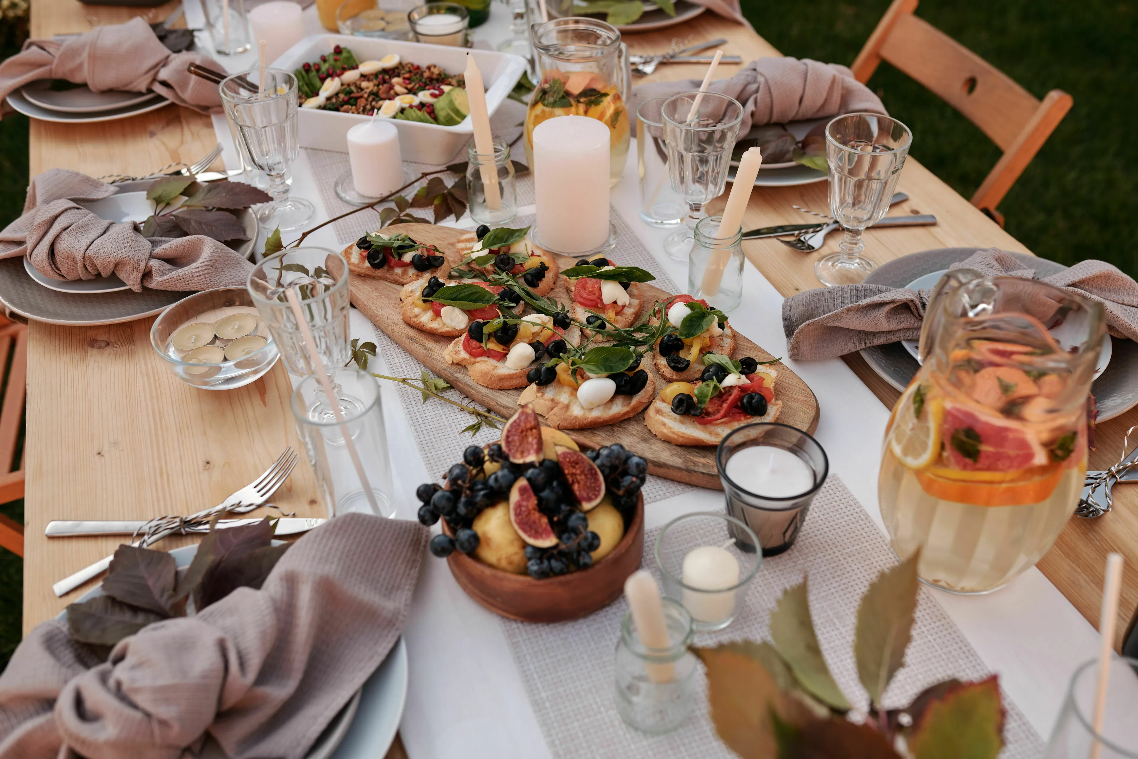 A beautifully set dinner party table outdoors with food and drinks, showing a seat at a big dinner party and stress response type.