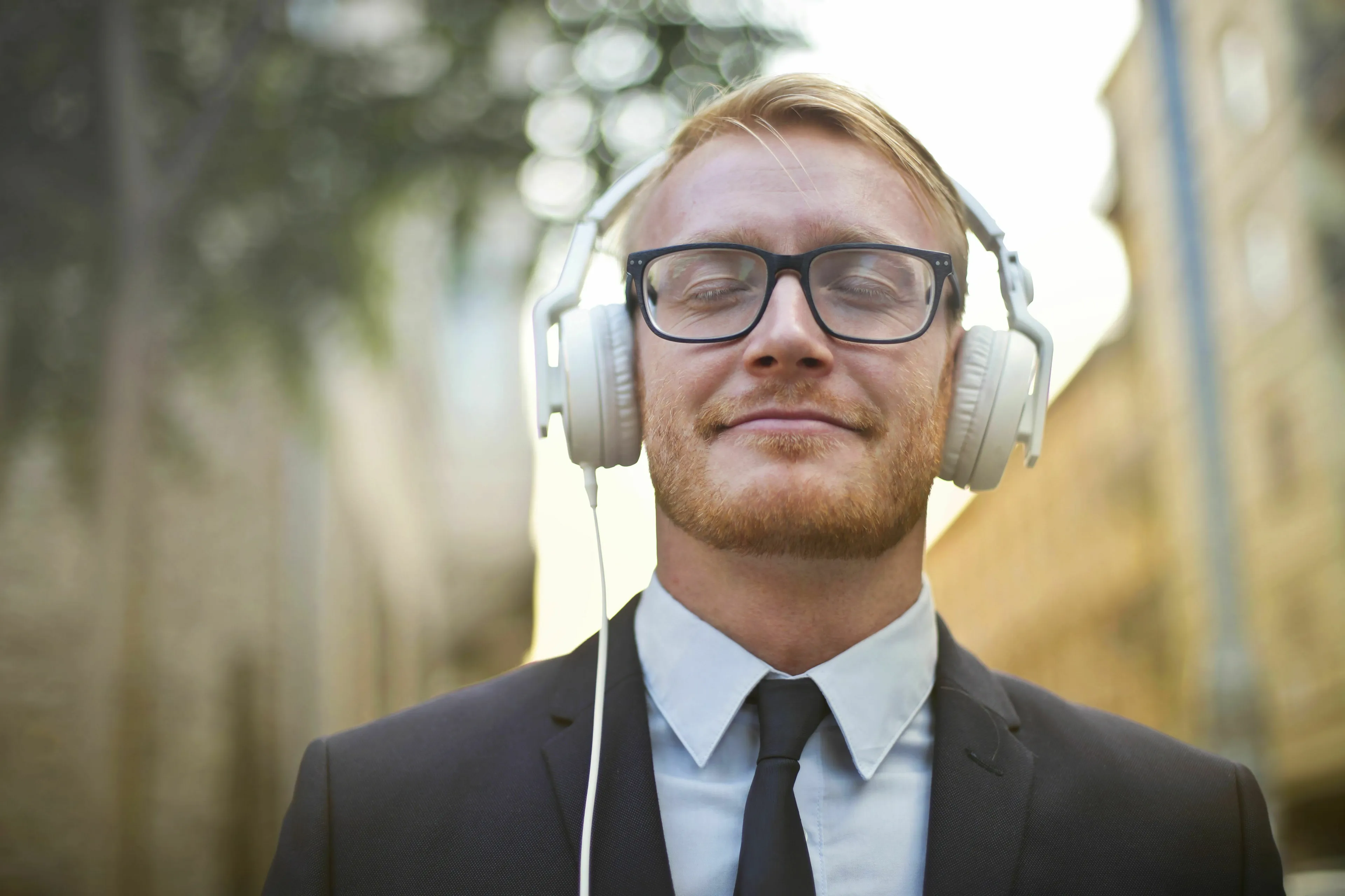 Man wearing headphones and glasses, enjoying music for a tense day to manage his stress response.