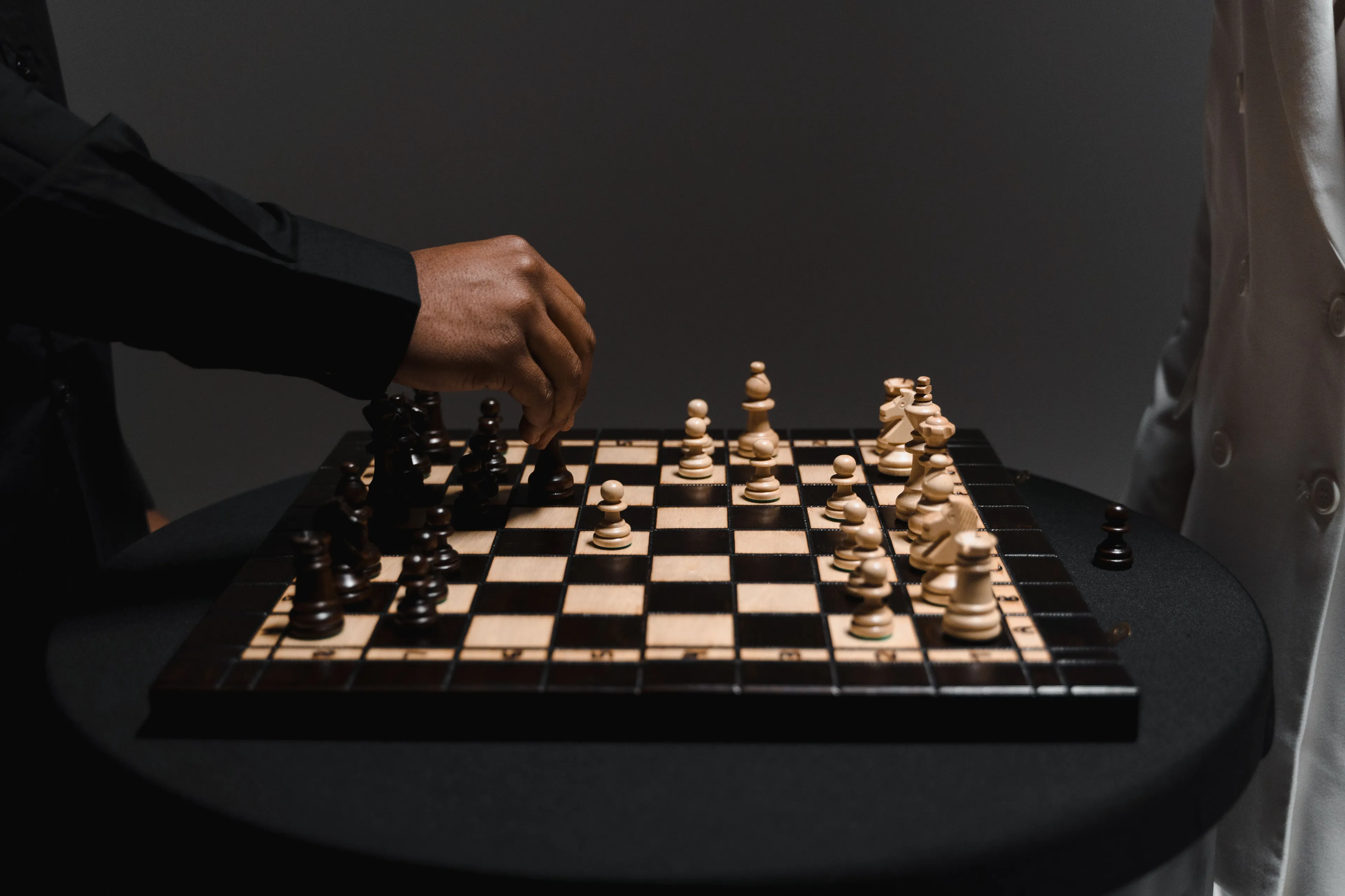 Two people engaged in a competitive game of chess on a dark background.
