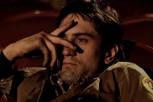 A close-up of Travis Bickle in Taxi Driver, showing his obsession. He is deep in thought, hand covering his face.