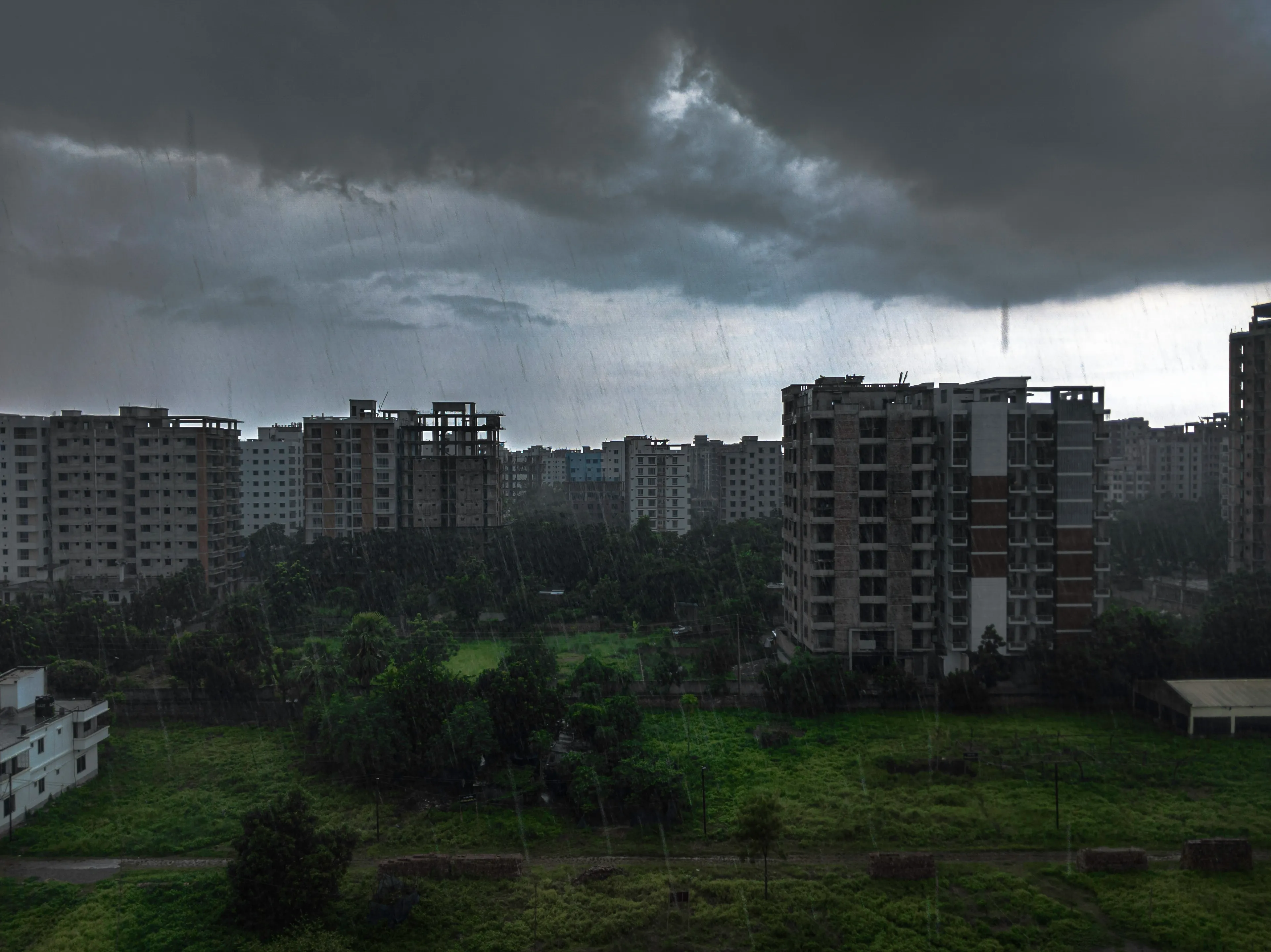 A cityscape during a drizzle, with dark clouds overhead and rain falling, showing a weather scene.