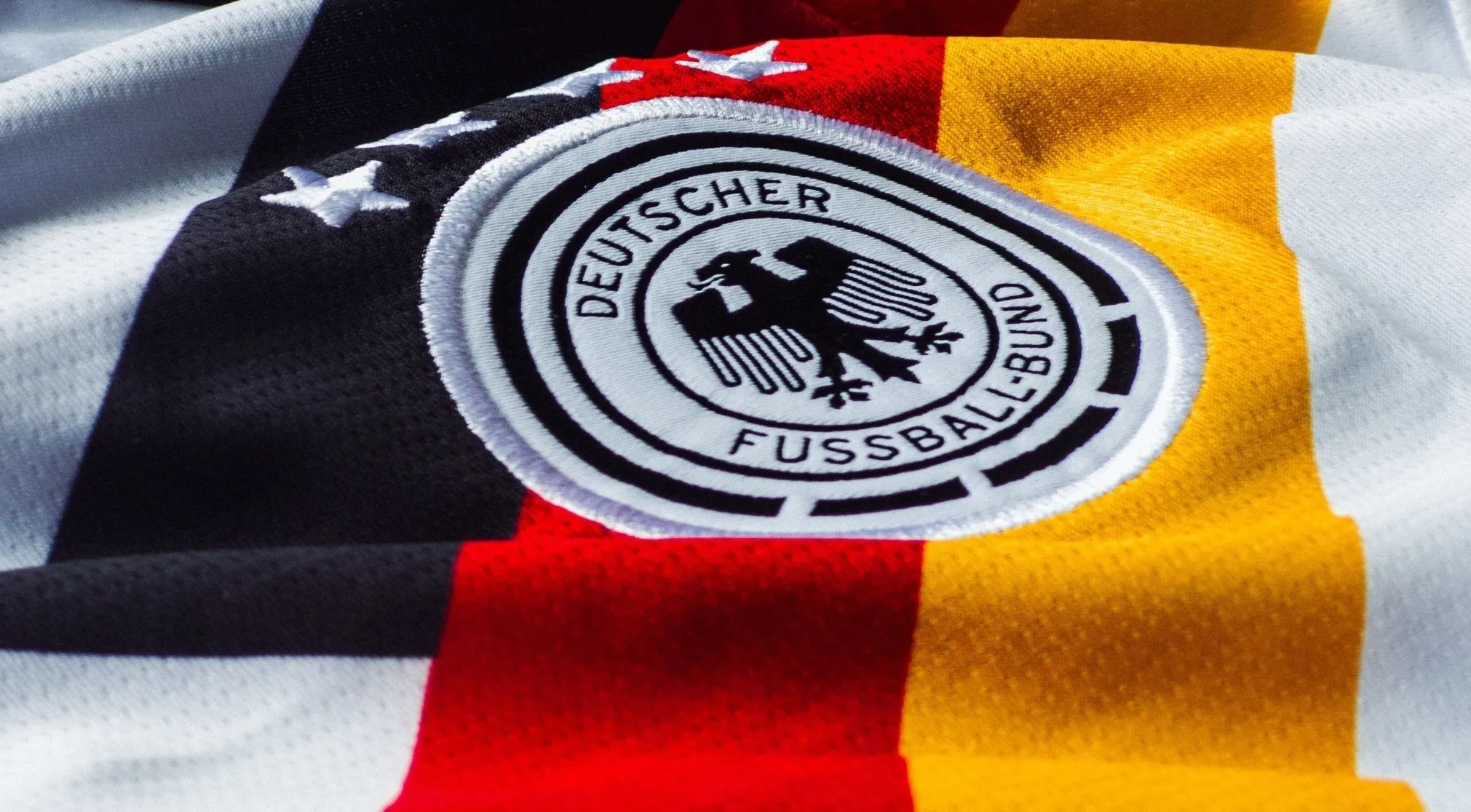 Close-up of a FIFA World Cup Germany national football team jersey with the DFB logo and four stars.