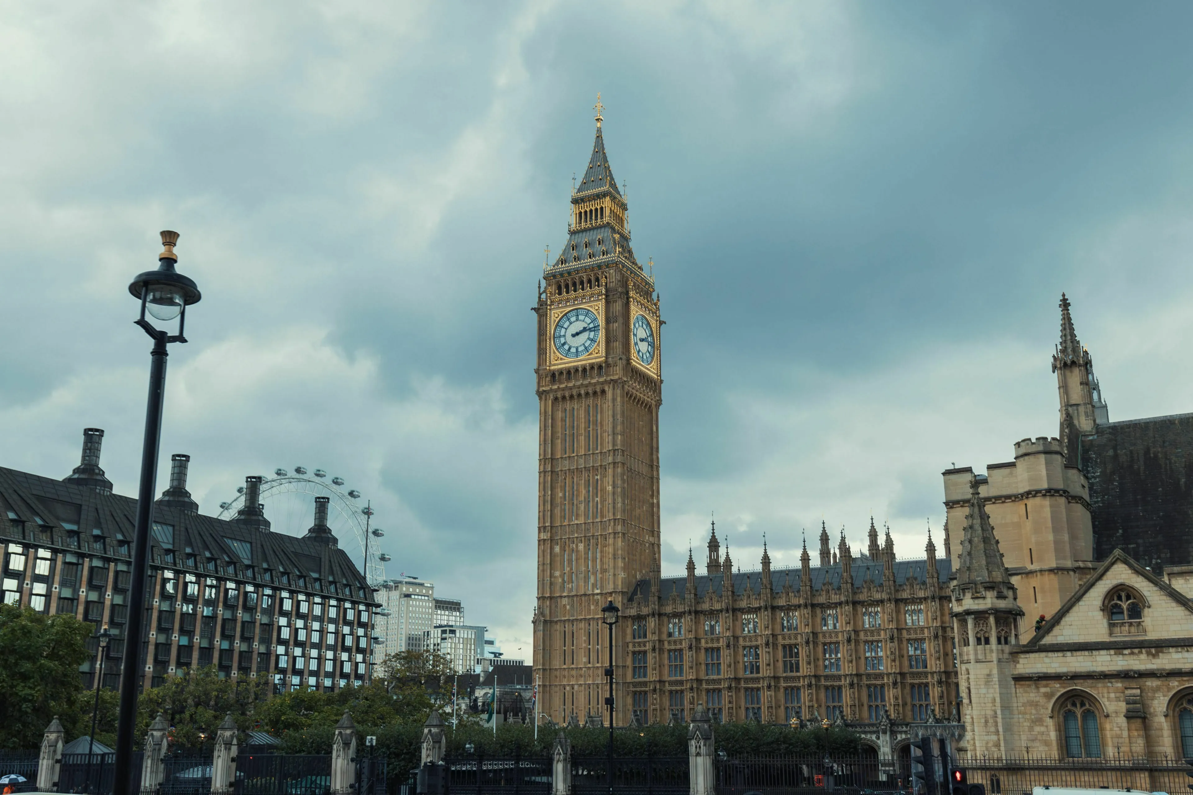 The iconic Big Ben clock tower next to the Palace of Westminster in London, England, under a cloudy sky.