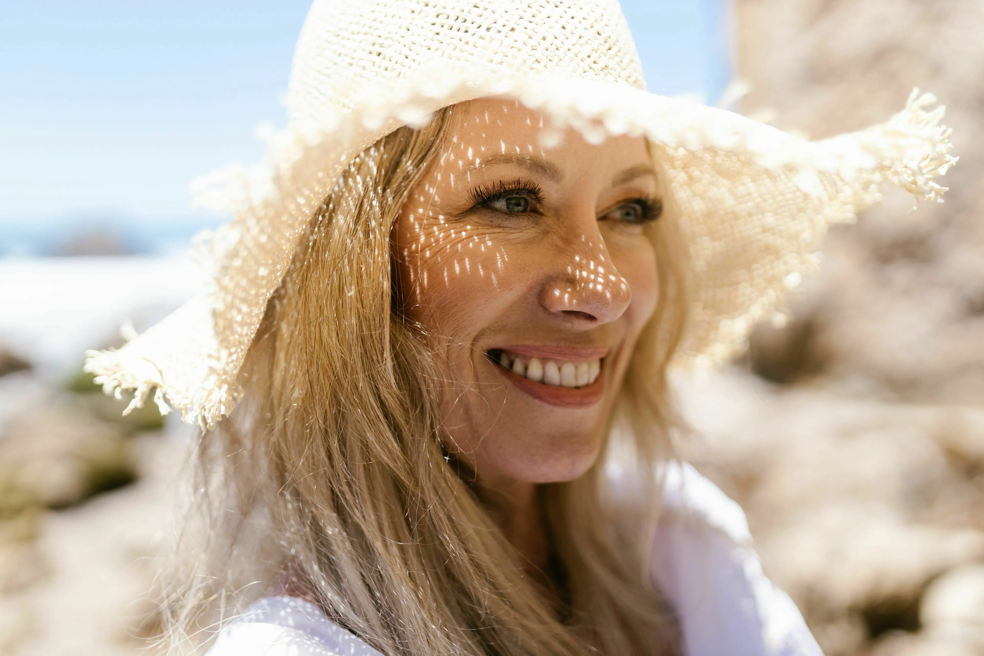 Woman in a straw hat, smiling, representing the vitamin produced by skin exposed to sunlight for a Pub Trivia Quiz.