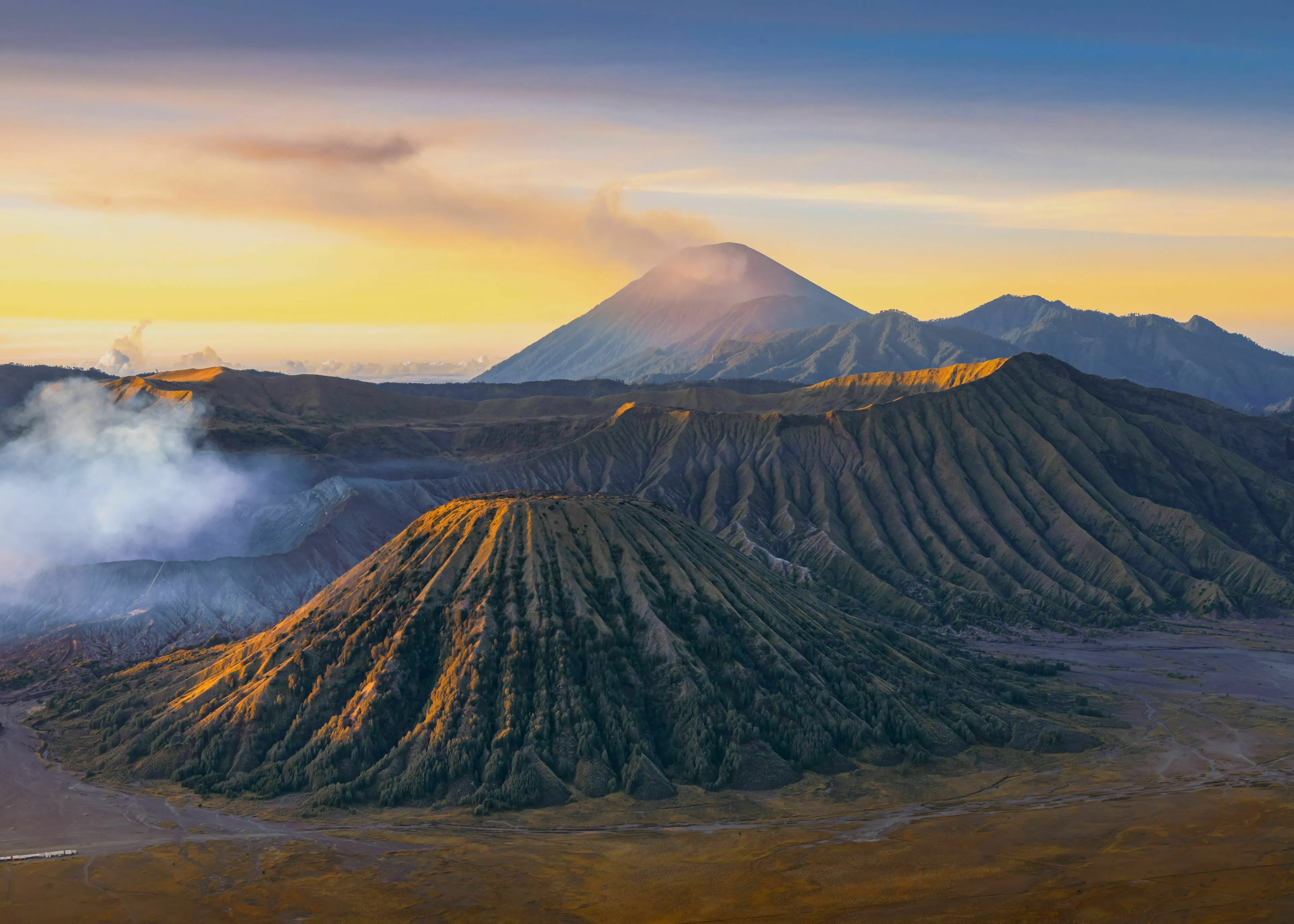 A pub trivia quiz question: The study of volcanoes is called what? Majestic volcanic landscape with smoking peaks at sunrise.