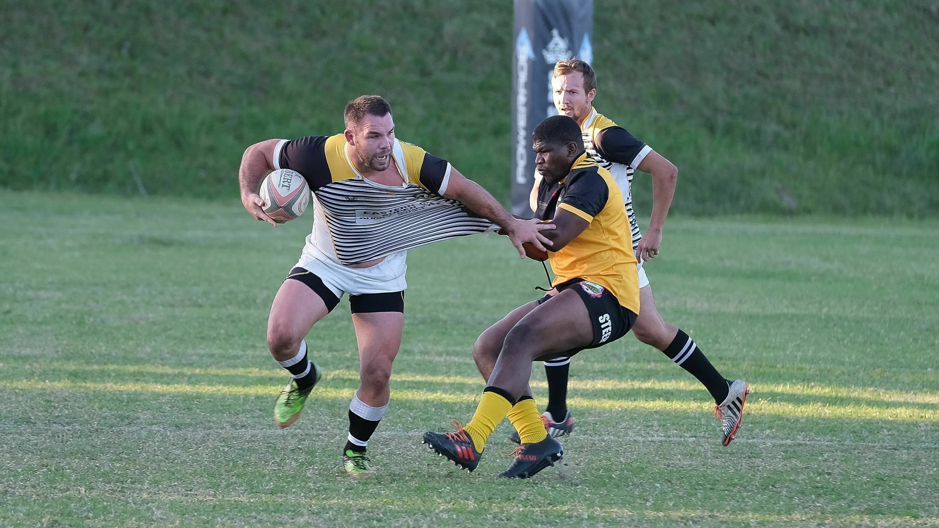 A pub trivia quiz question: How many points is a try worth in rugby union? Two rugby players mid-game on a green field.