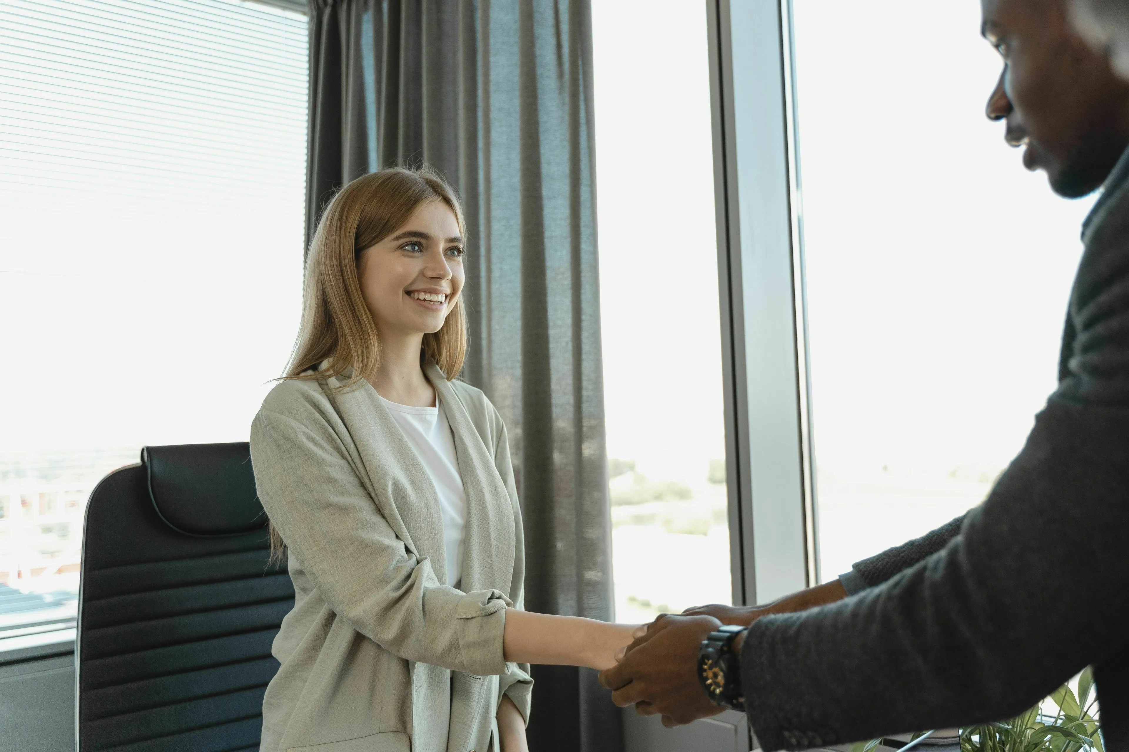 Two people shaking hands, illustrating the relationship with rules and onboarding documents at a new job.