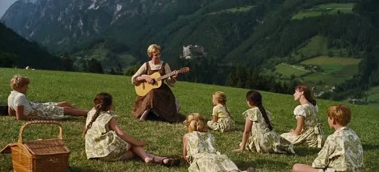 Julie Andrews and children singing in a field in a scene from The Sound of Music.