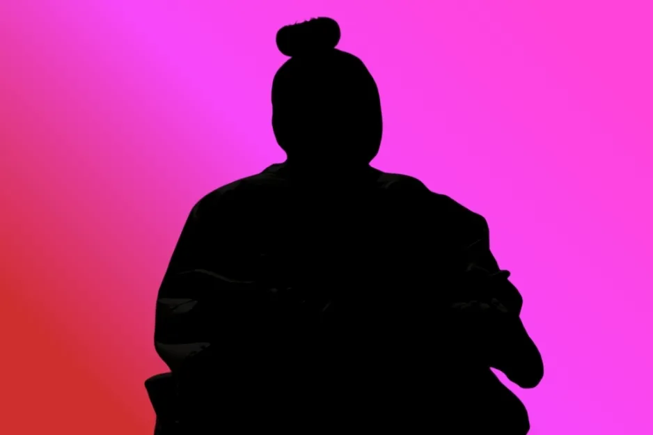 Silhouette of Kevin Malone from The Office (2005) with a top bun, sitting against a pink background.