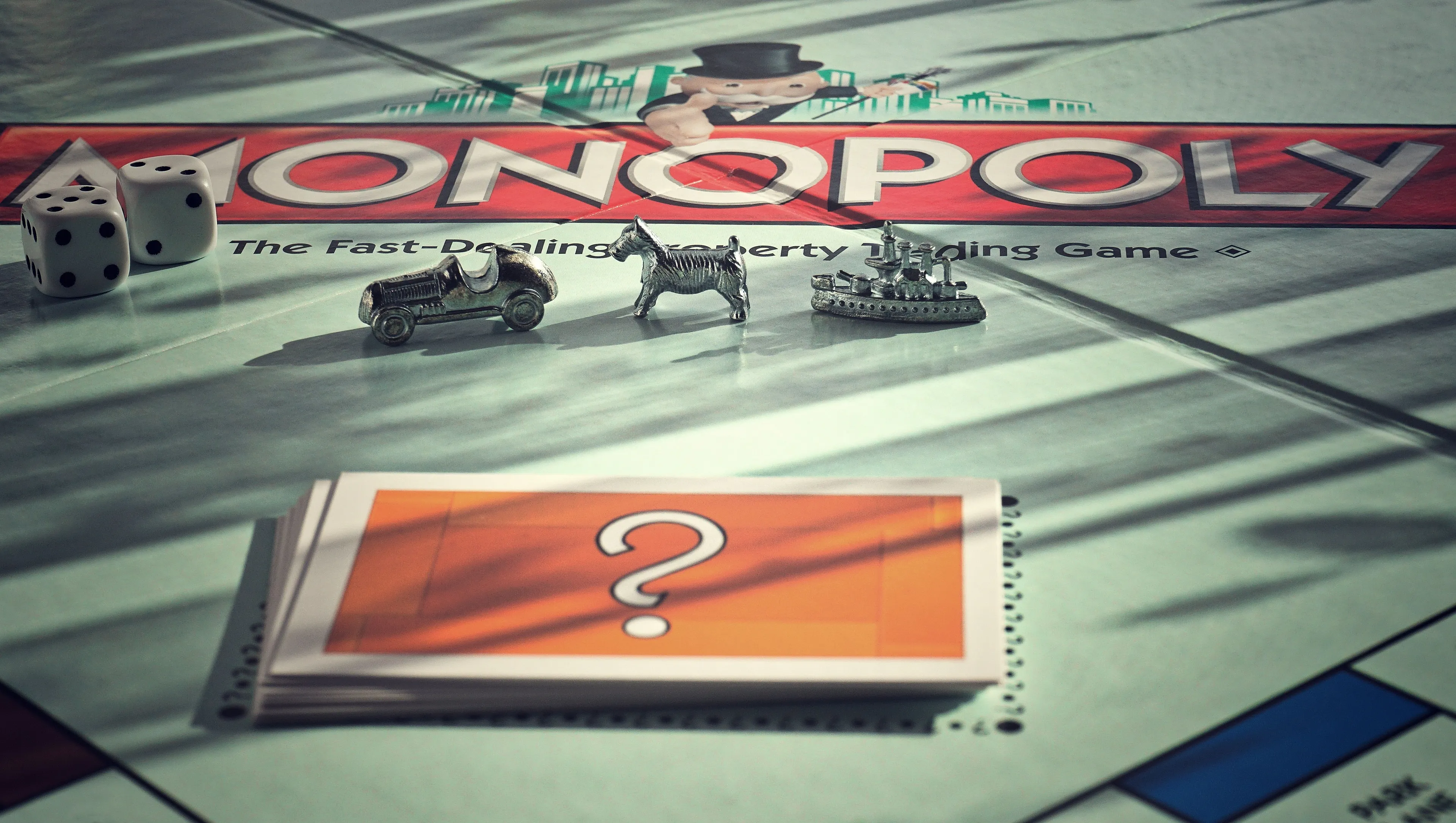 A close-up of a Monopoly board with game pieces and Chance cards, highlighting the childhood game Monopoly.