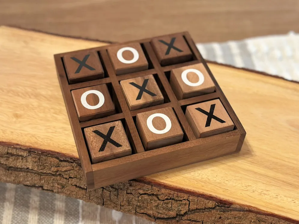 A wooden tic-tac-toe board with X and O pieces on a rustic wooden surface, a favorite childhood game.