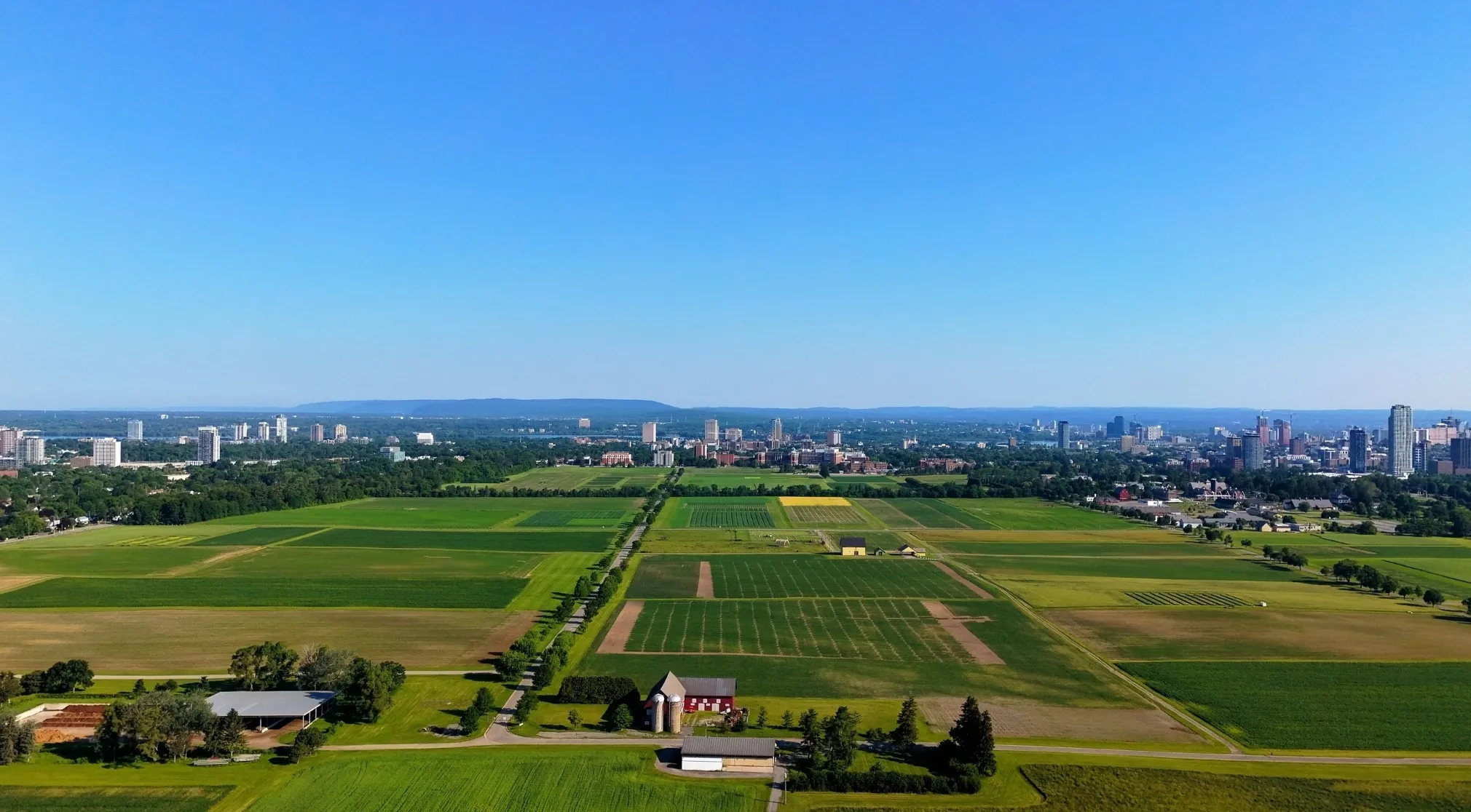 Aerial view of a city skyline across green fields, illustrating the difference between a city and country town. WWI recruit test theme.
