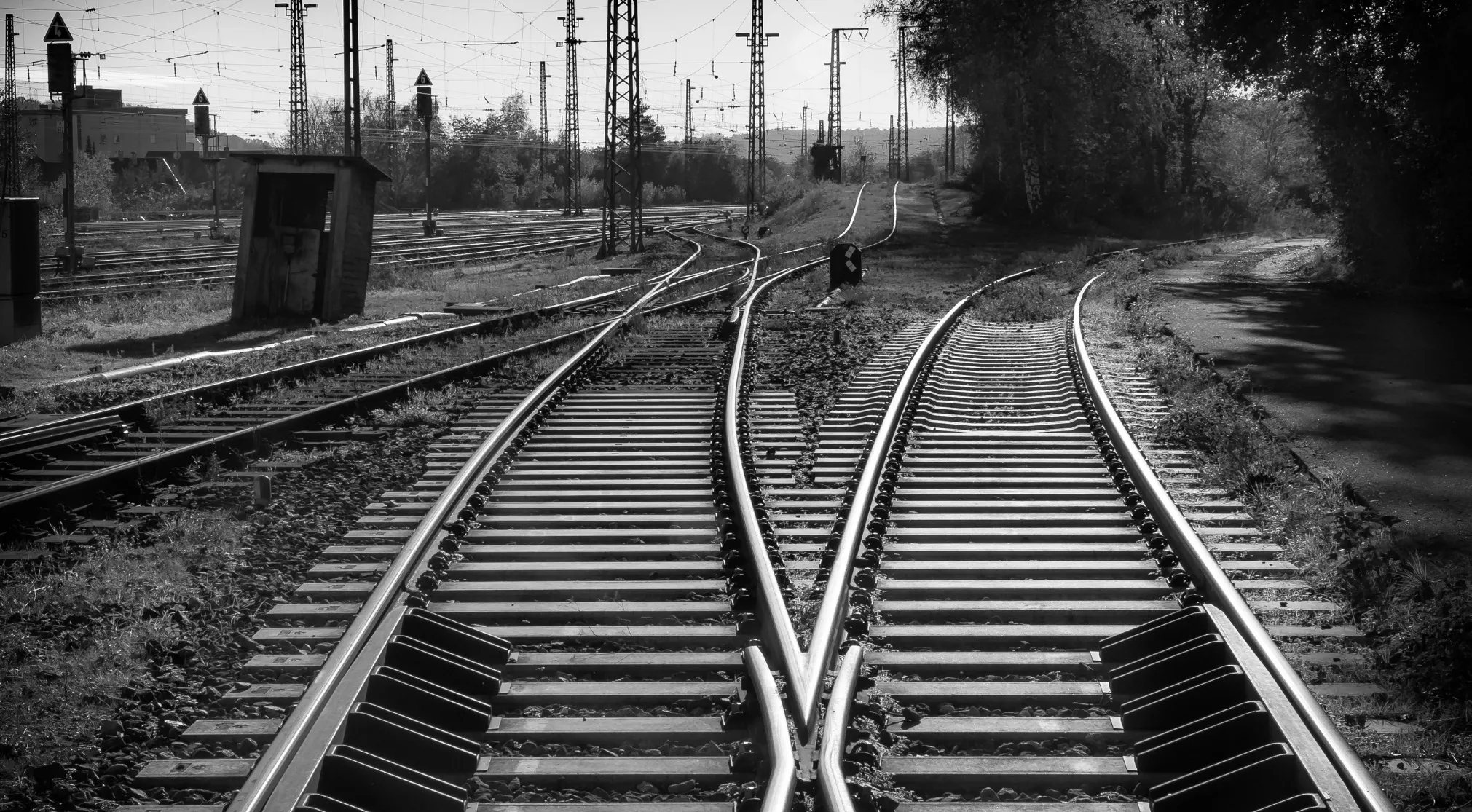Black and white image of converging railroad tracks, power lines, and a small hut. A WWI recruit test image.