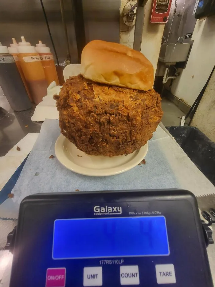 A massive fried patty on a bun placed on a scale representing a questionable food combo.