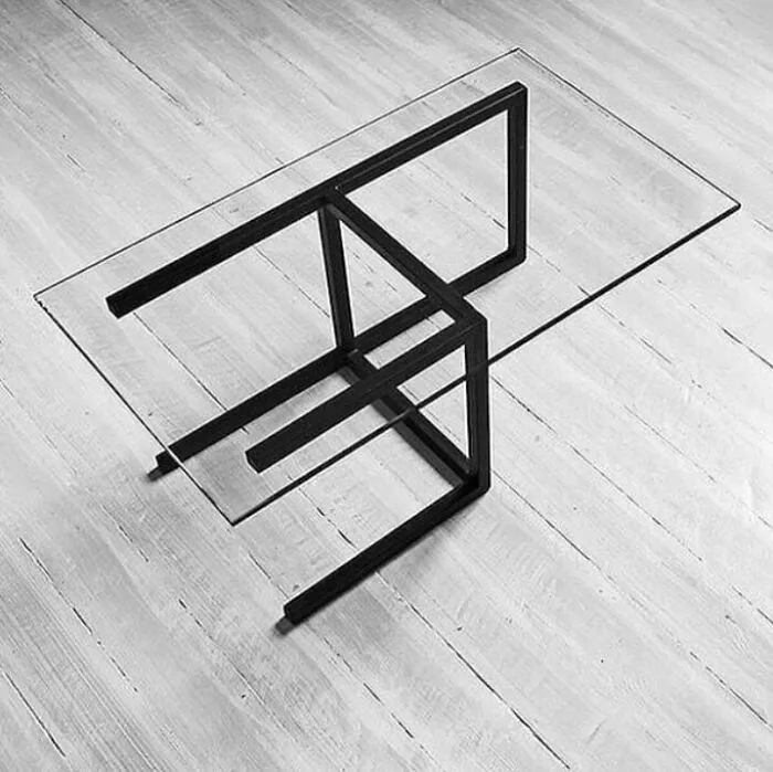 A modern glass coffee table with an abstract black metal base, showcasing innovative furniture design.