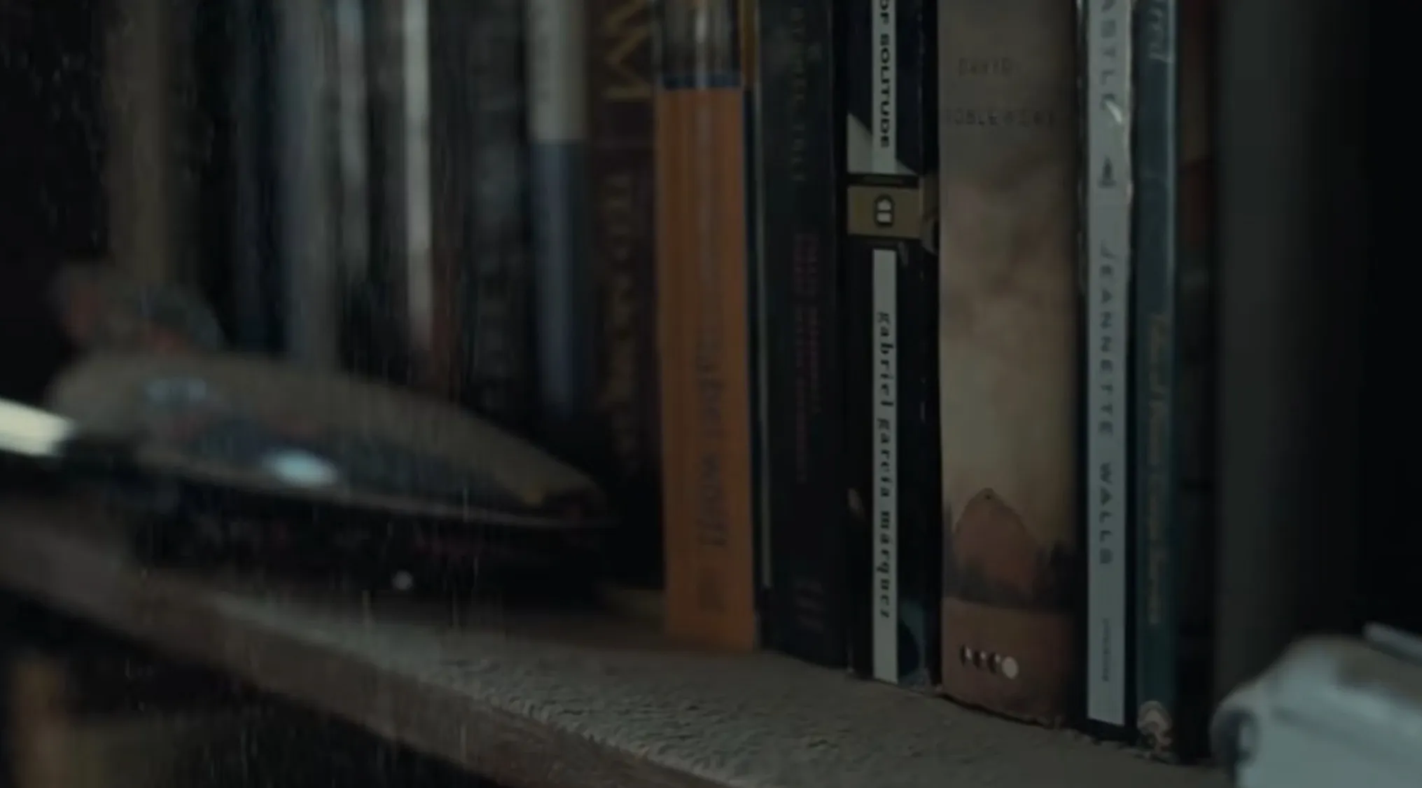 A dusty bookshelf with books and a model spaceship, hinting at an opening movie scene.