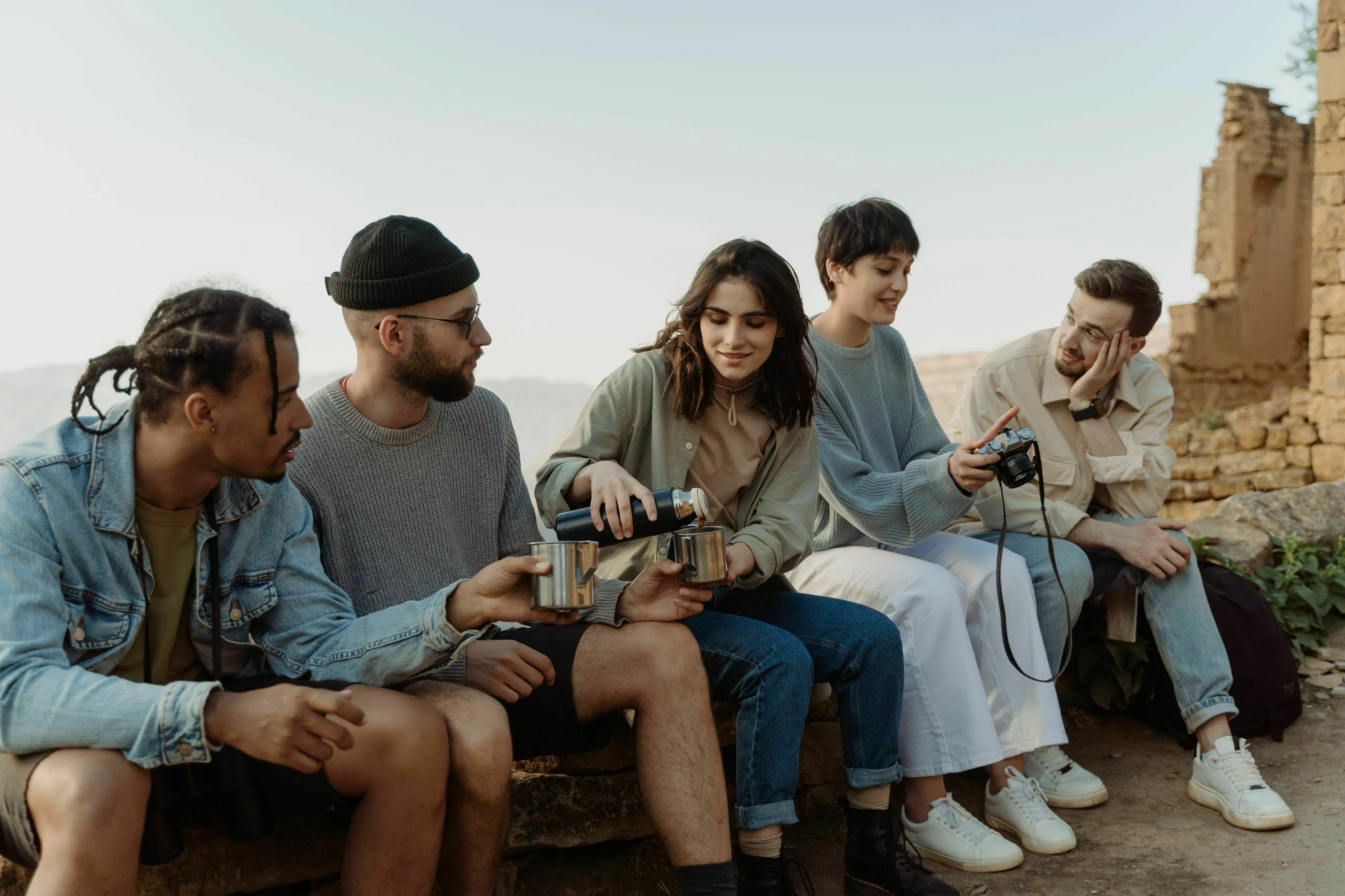 A diverse group of friends, representing an extinct species social dynamic, enjoying a beverage outdoors.