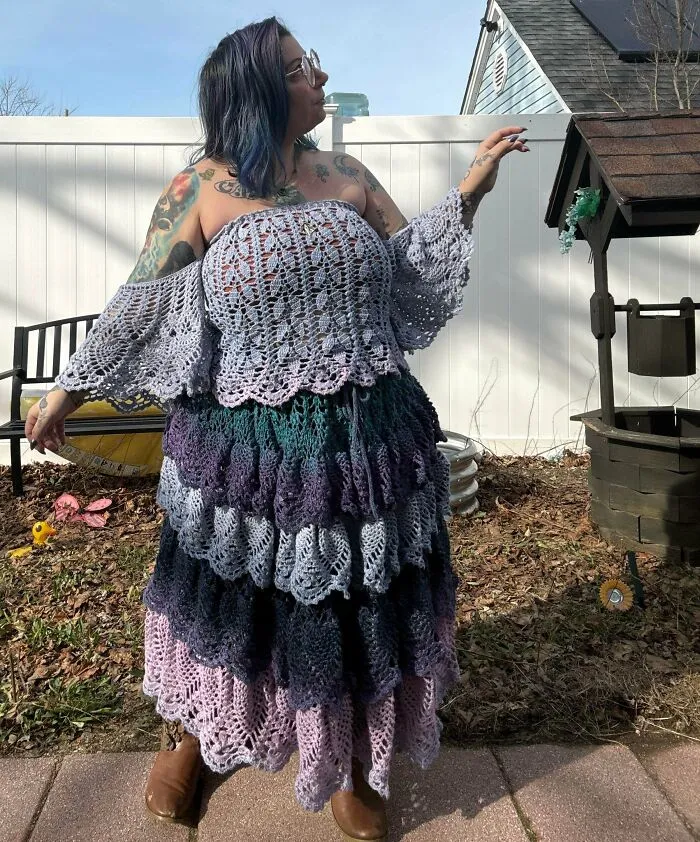 Woman wearing colorful layered crochet dress with wide sleeves outdoors