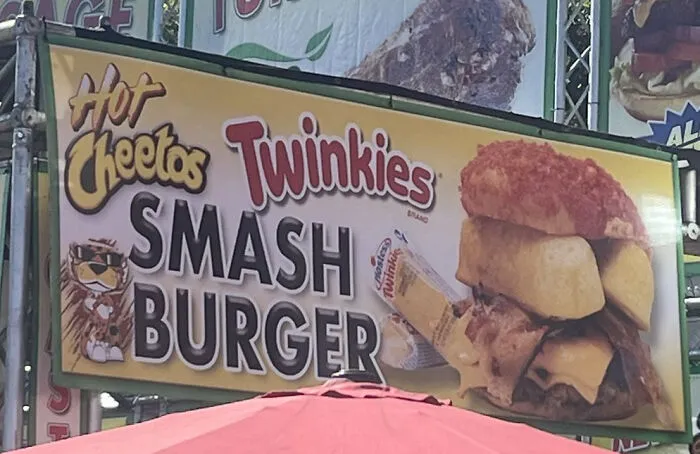 A sign for Hot Cheetos Twinkies Smash Burger showing a questionable food combo.