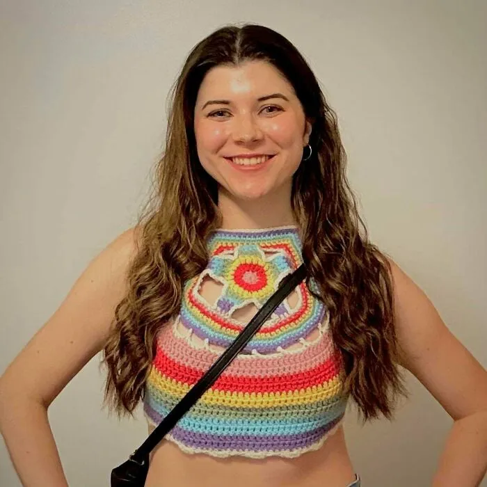 Smiling woman in colorful striped crochet crop top creative crochet project