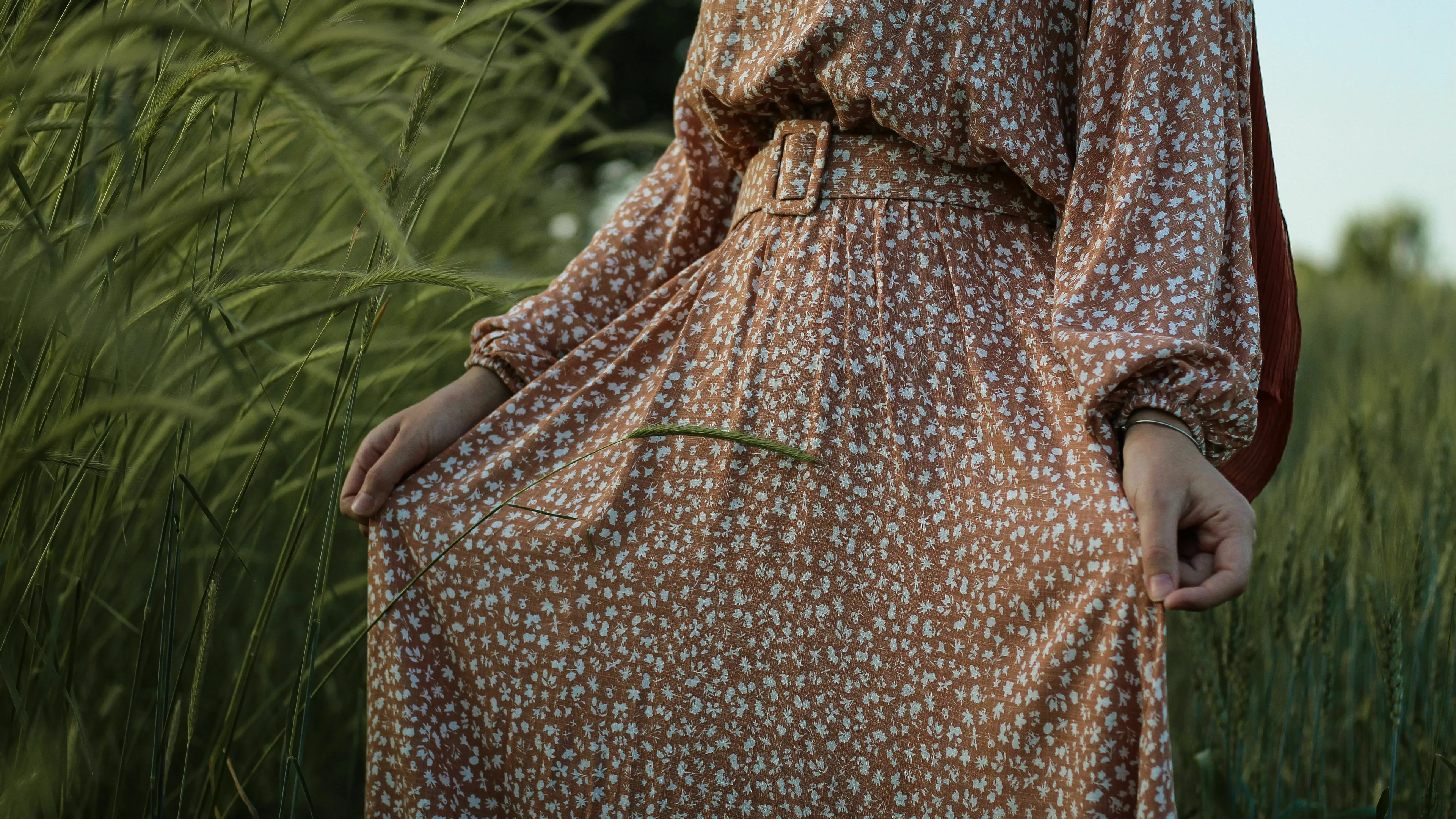 Someone compliments your outfit. A woman in a floral dress stands in a field of tall grass.