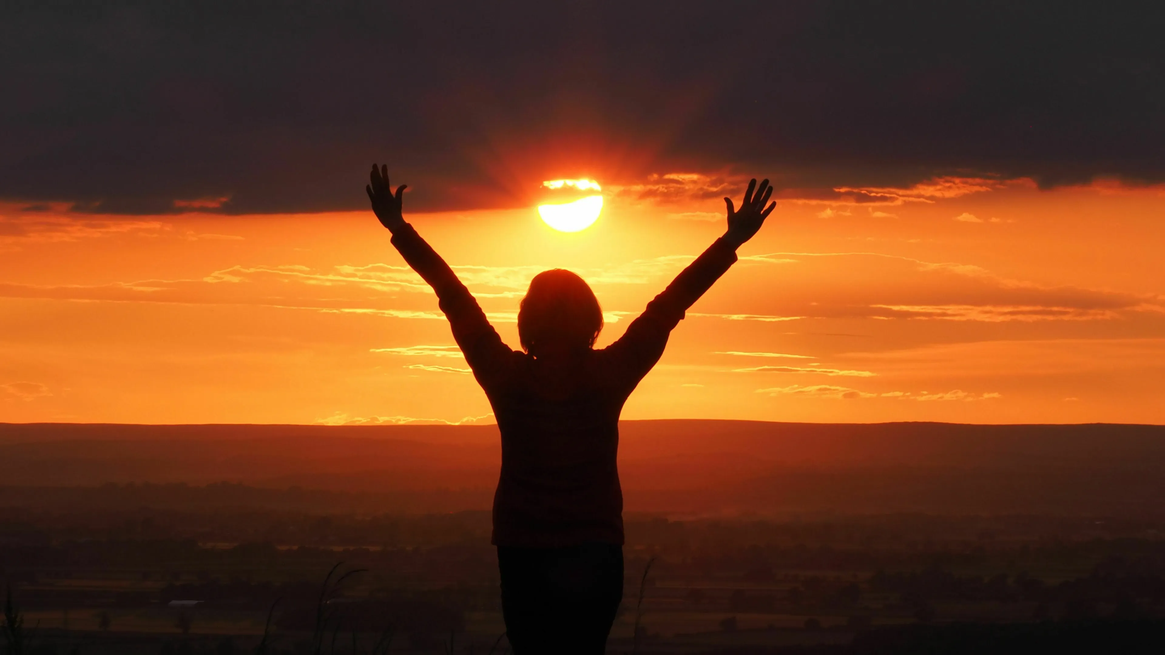Silhouette of a person with arms raised against a sunset, depicting a good day ending with validation.