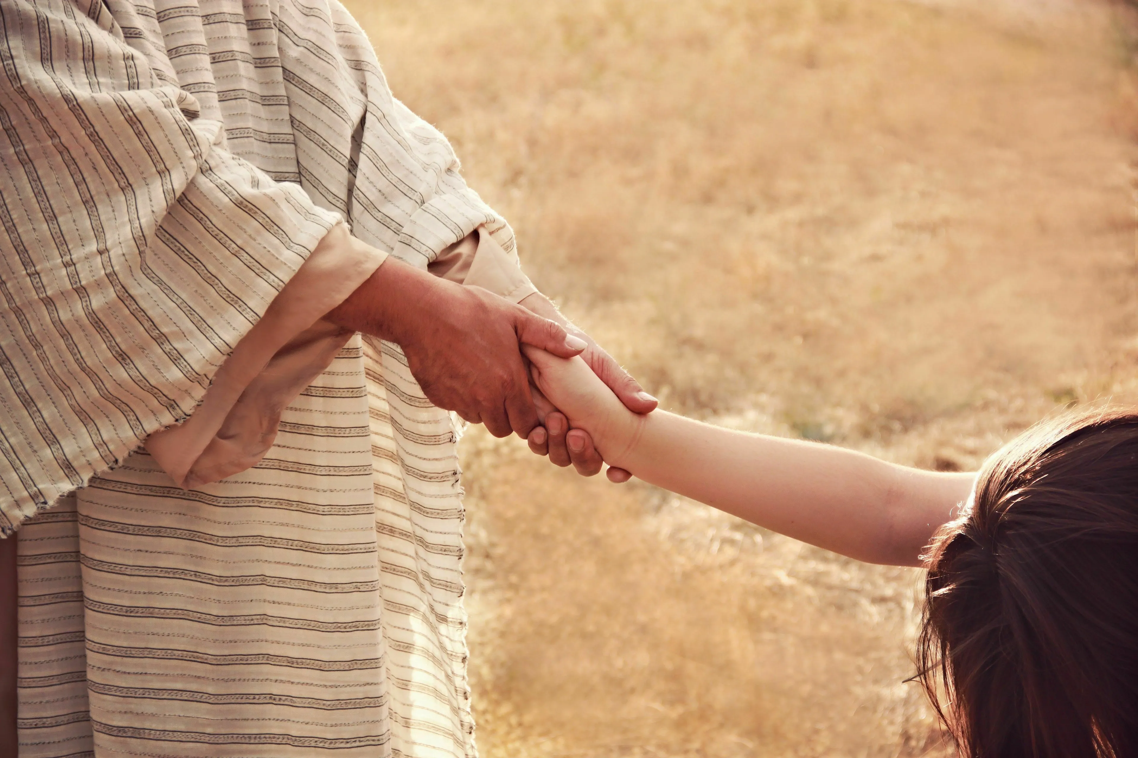 A person in robes reaching out and holding the hand of a child, symbolizing how to seek validation.