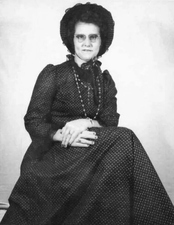 A vintage black and white photo of a woman in a period dress and hat, a historical timeline fact in fashion.