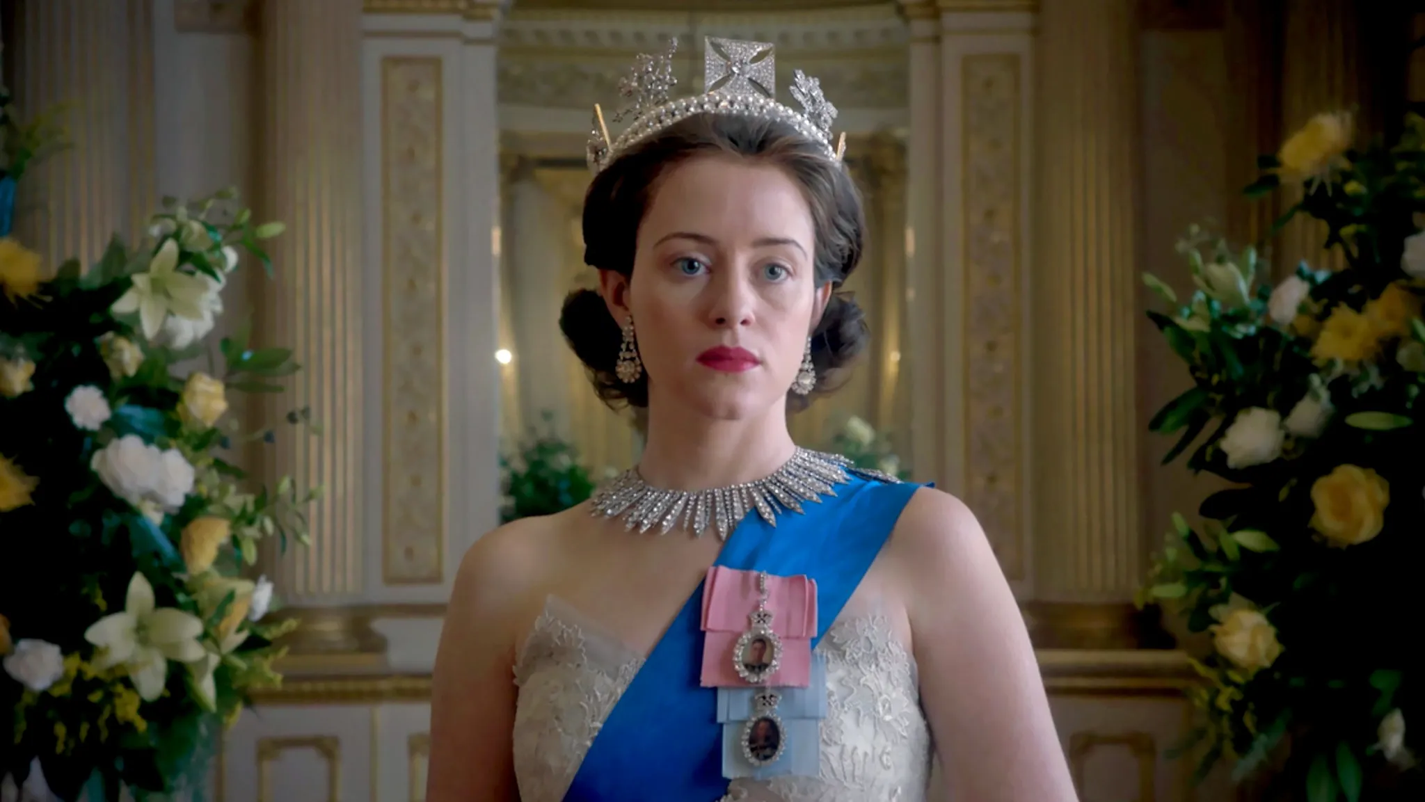 Claire Foy as Queen Elizabeth II in The Crown, wearing a crown, necklace, and sash.