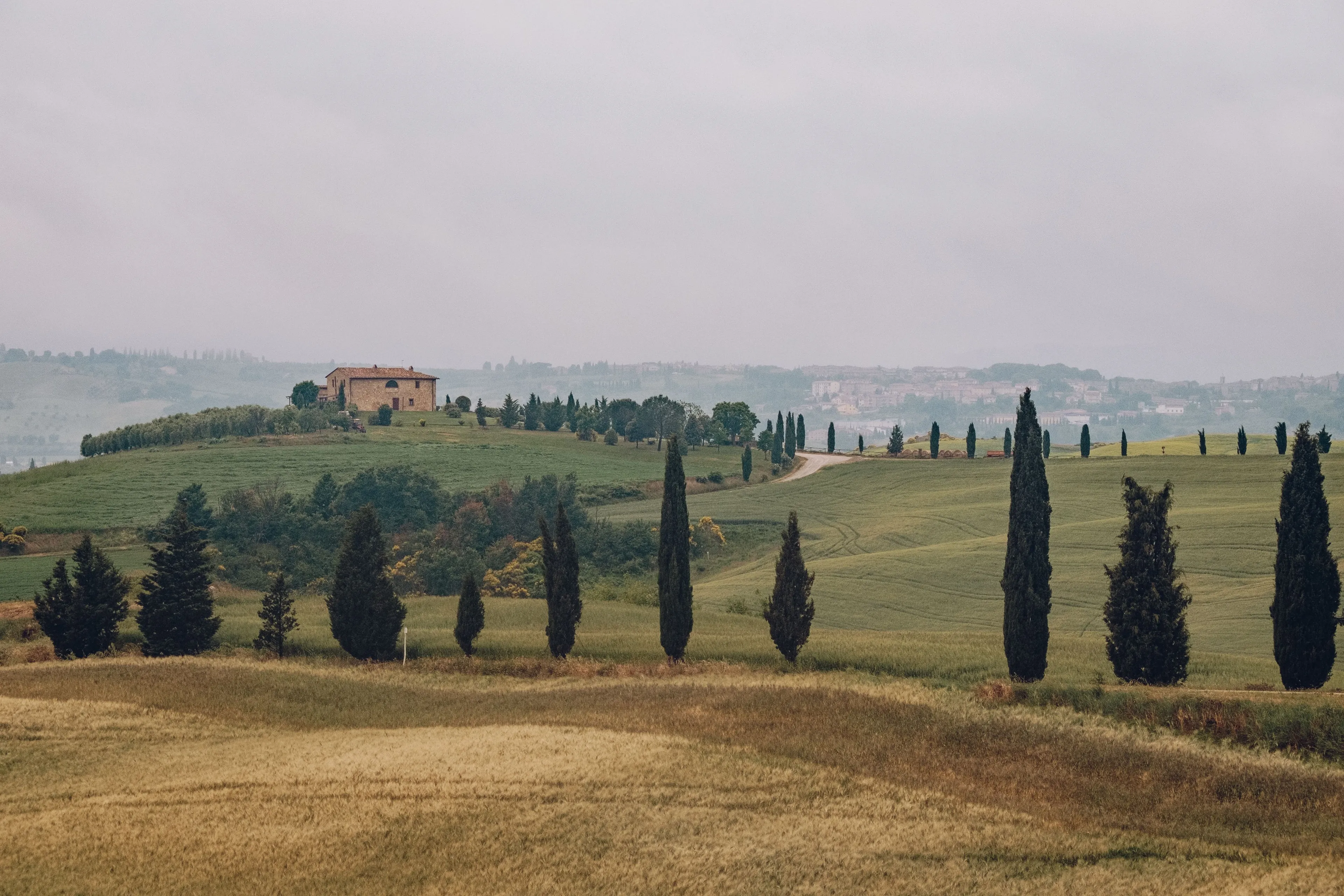 Rolling hills of Tuscany with cypress trees and a farmhouse, showcasing the Italian countryside as a relaxing vacation spot.