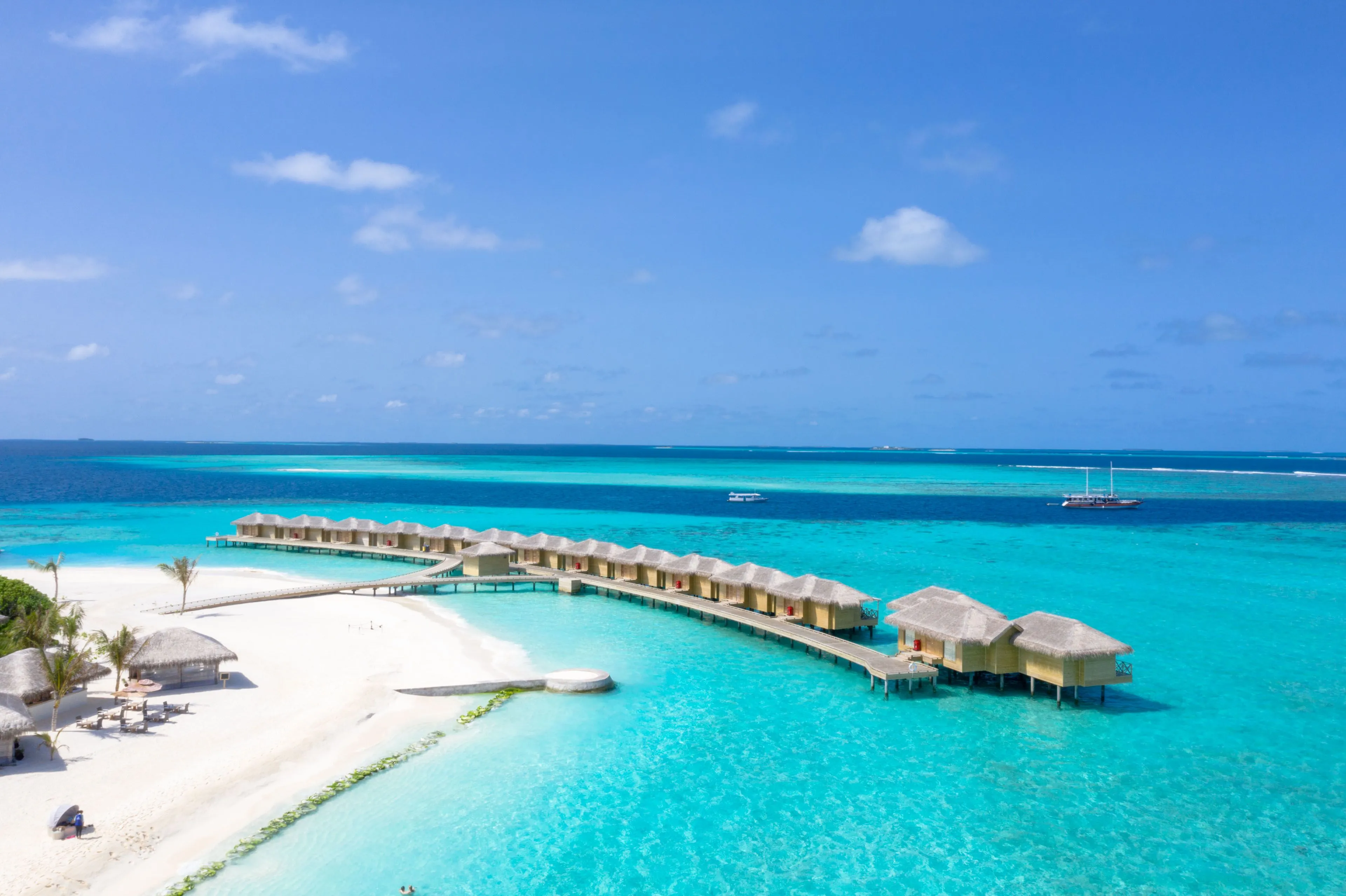Aerial view of luxurious overwater bungalows extending into the crystal-clear turquoise waters of the Maldives, a perfect vacation spot.