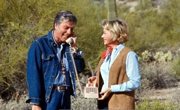 Two smiling people using a vintage phone outdoors, part of history-changing timeline facts.