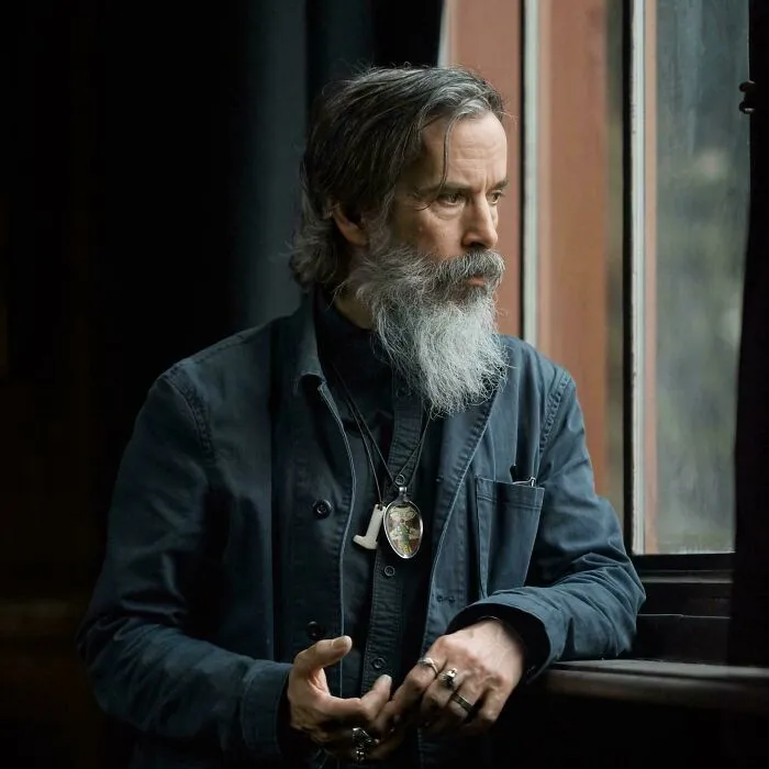 A thoughtful man with a long grey beard, reflecting on timeline facts and changing his sense of history.