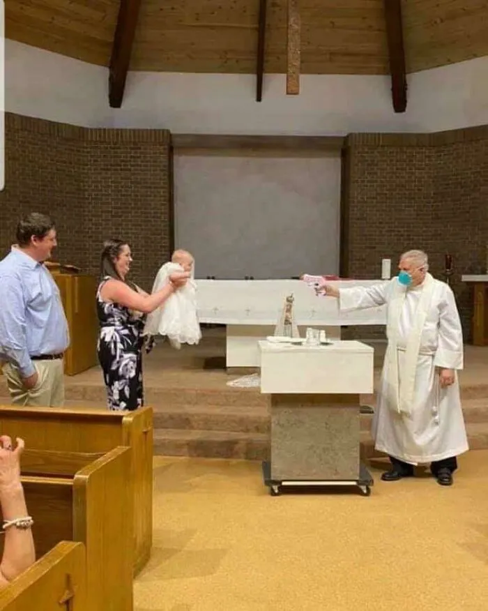 A priest performing a christening while social distancing, reflecting a unique moment in history.
