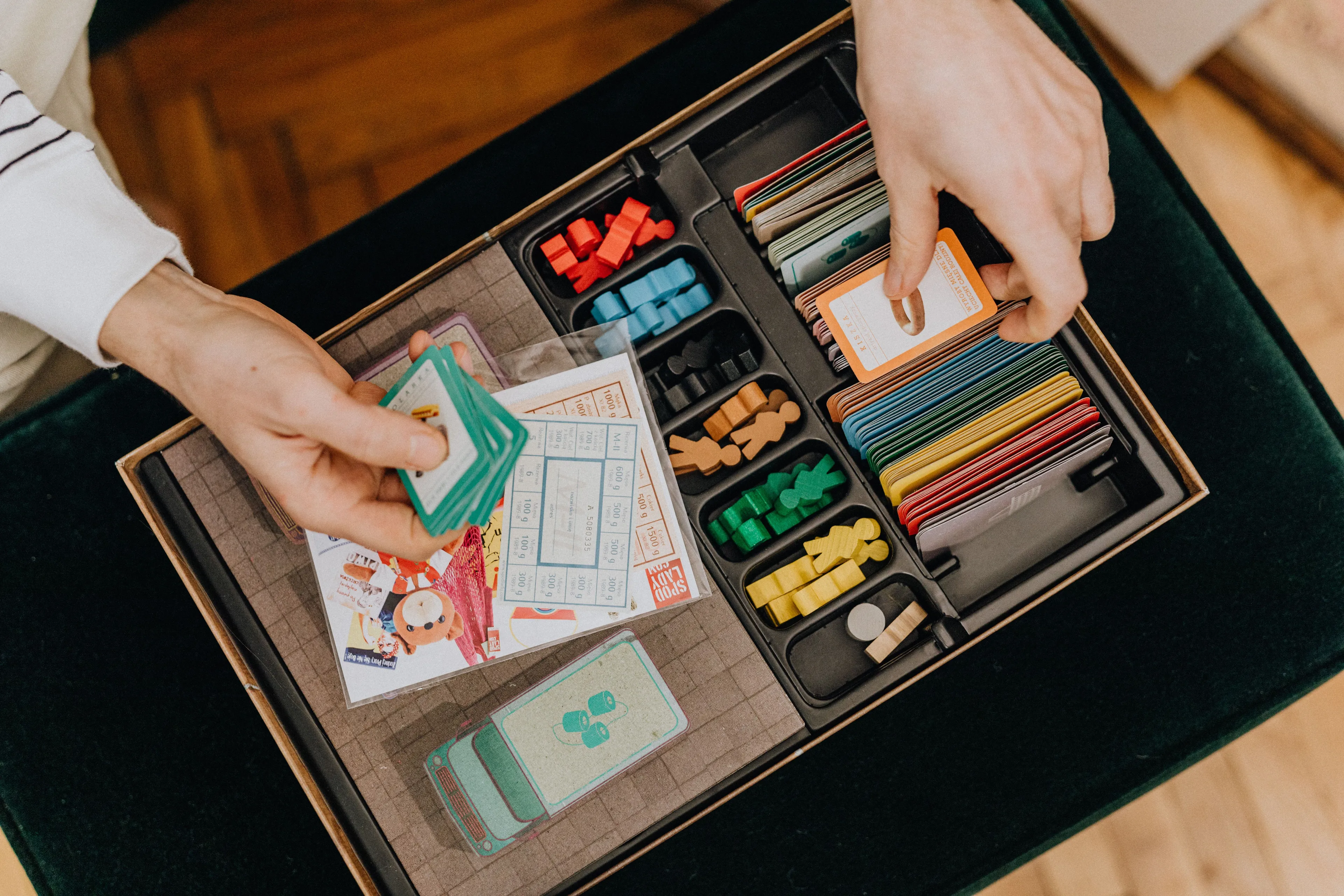 Game night during a rainy afternoon, hands organizing board game pieces and cards.