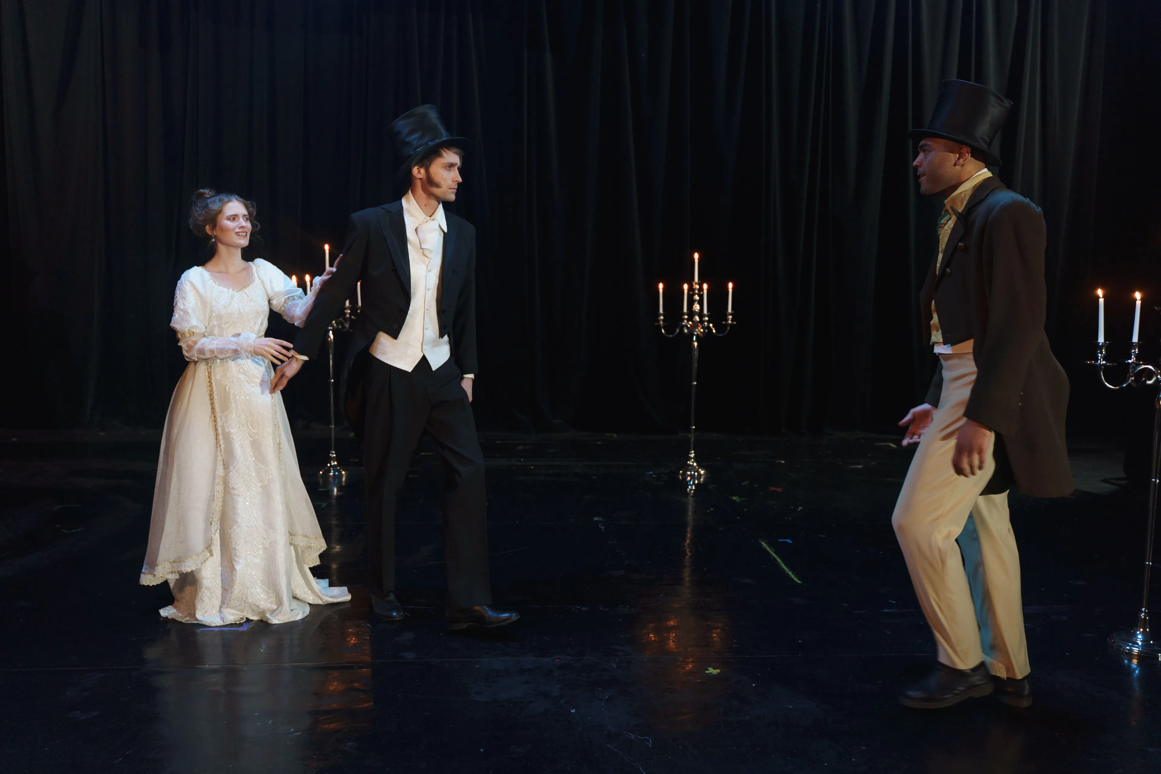 Three actors are performing on a stage with candelabras. Acting is a great hobby to master.