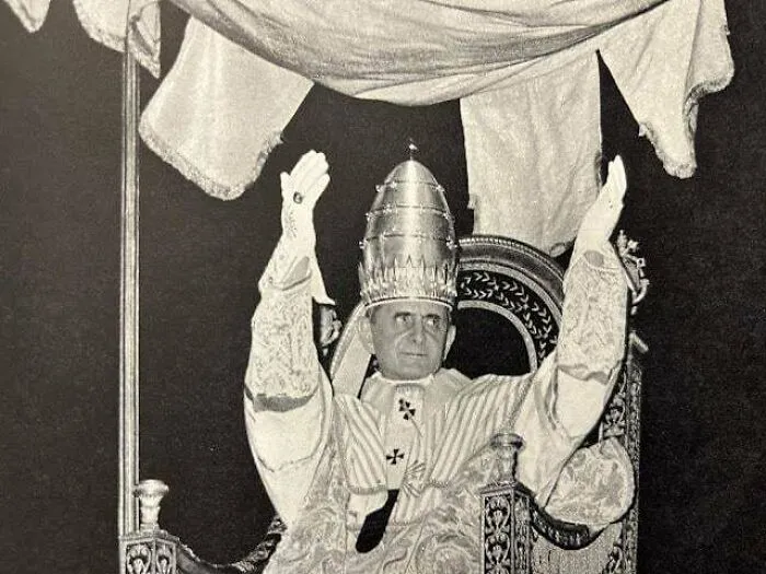 Pope Pius XII in ceremonial attire, raising his hands, a significant figure in religious history timeline facts.