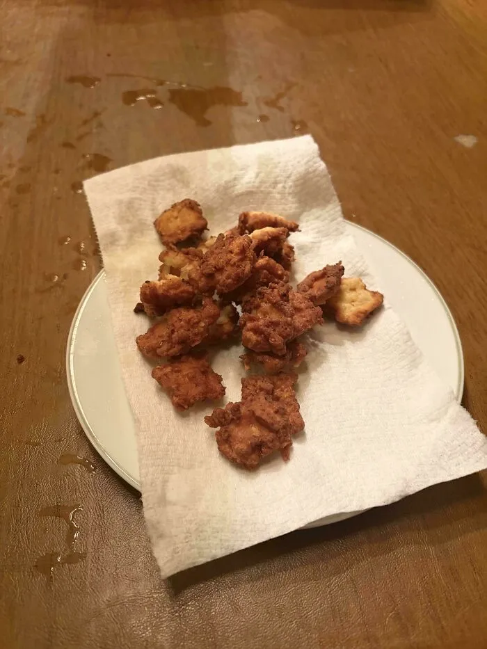 Disgusting food: Fried chicken pieces resting on a paper towel on a white plate, appearing greasy.