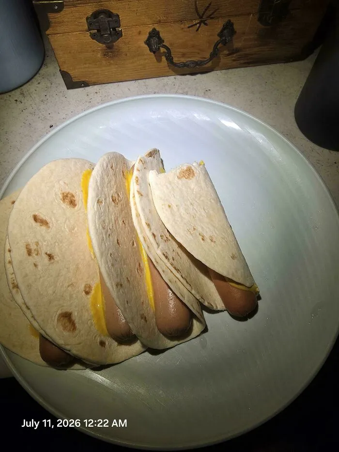 A plate of disgusting food: hot dogs with melted cheese wrapped in tortillas, poorly prepared.