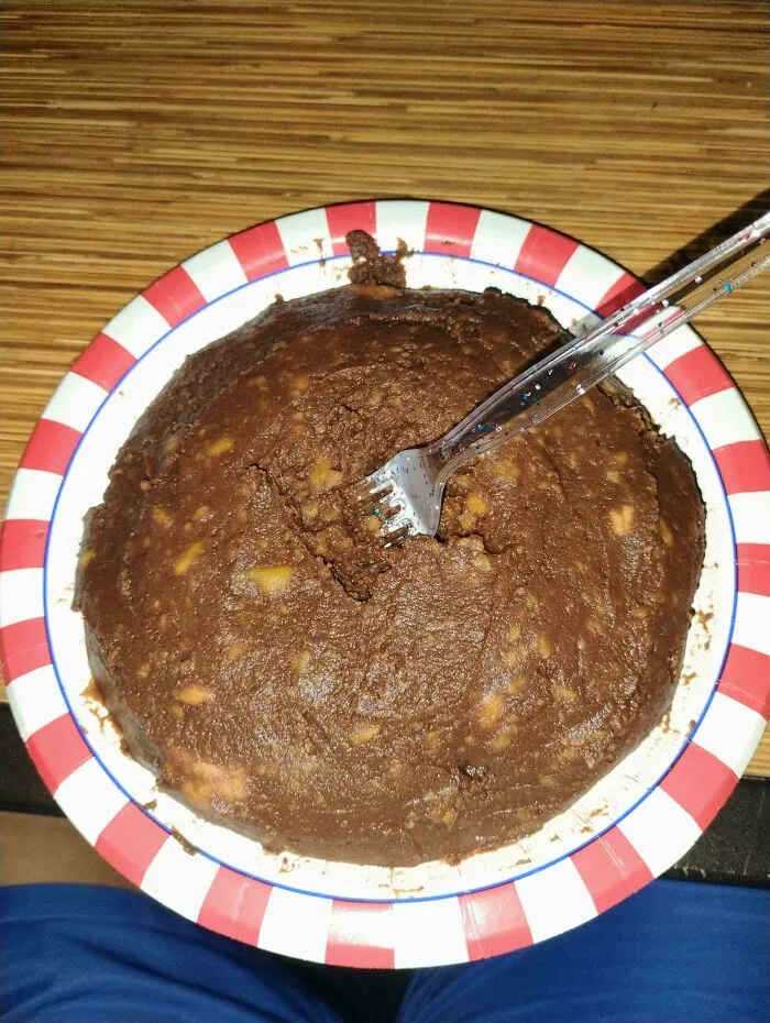 A chocolate cake-like dessert with a fork stuck in it on a red and white striped plate, an example of disgusting food.