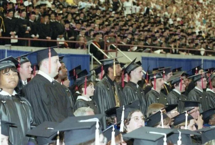 A wide shot of a college graduation ceremony, featuring many students in caps and gowns, reflecting significant timeline facts.