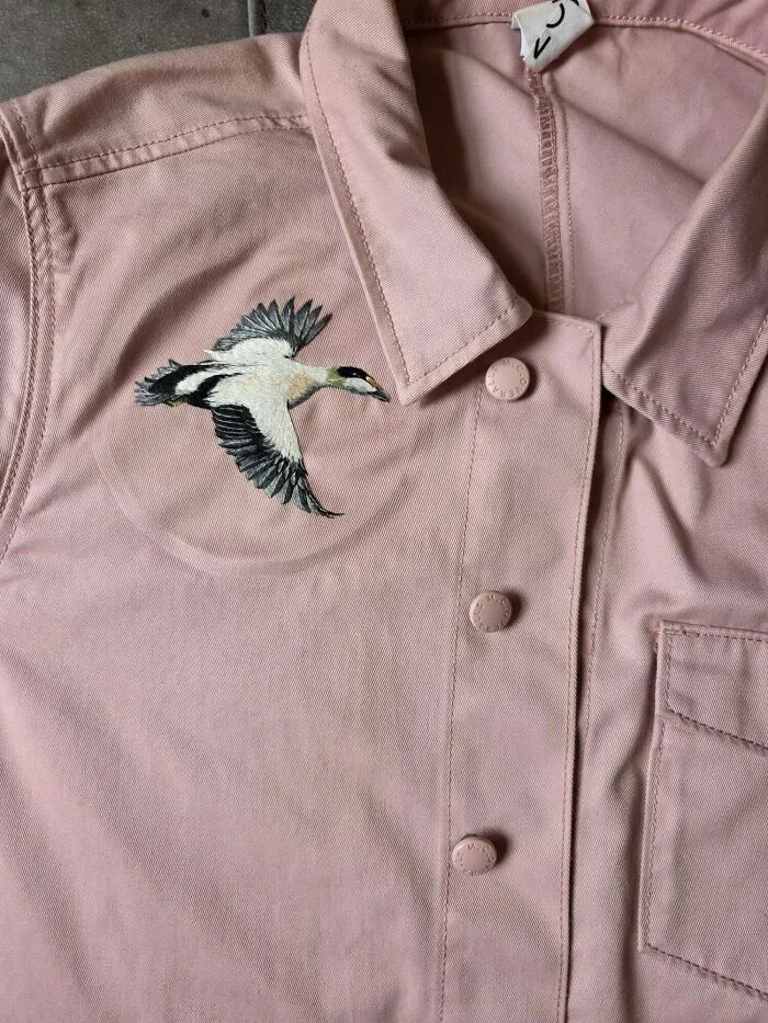A detailed bird embroidery on a pink button-up shirt jacket