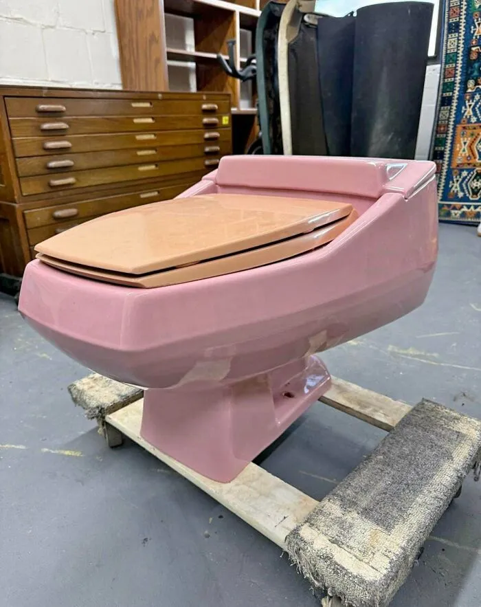 A pink vintage toilet with a wooden seat, a distinct piece of 1970s and 1980s interior design.