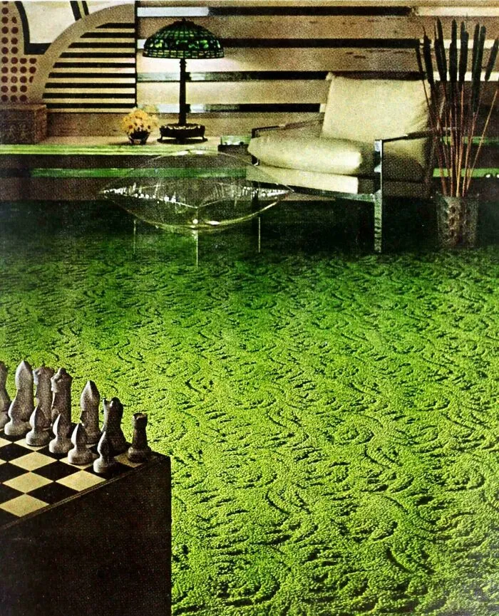 A vibrant green shag carpet with a swirling pattern, a clear coffee table, and a modern chair, reflecting 1970s and 1980s interior design trends.
