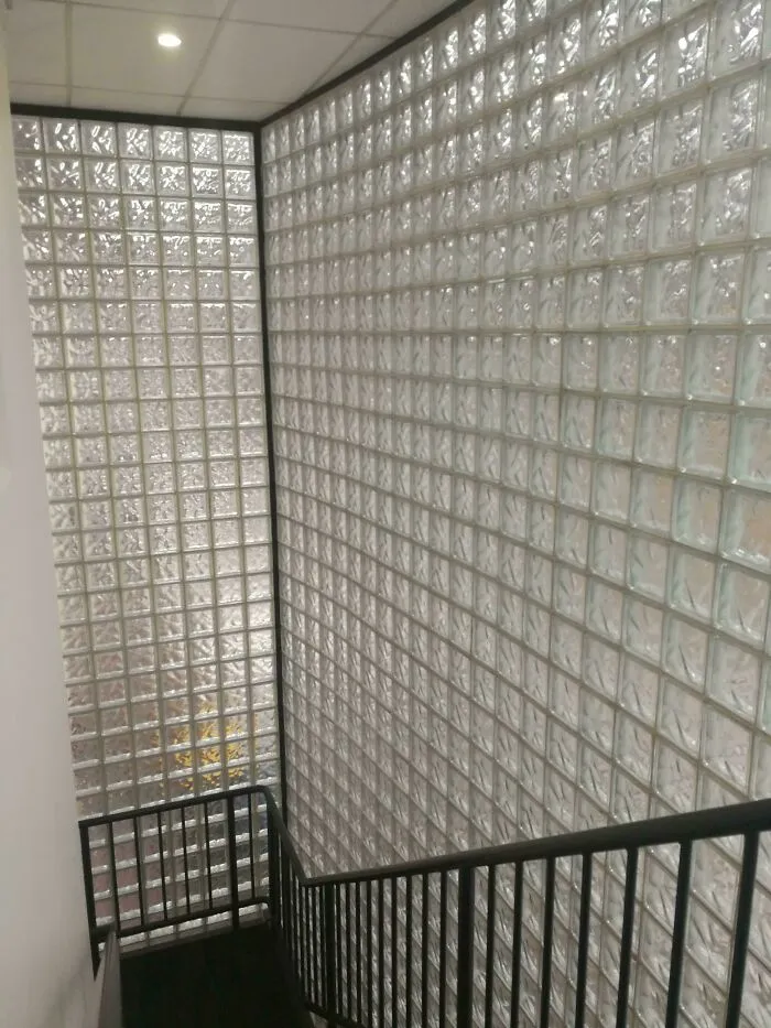 A staircase alongside a large wall made of glass bricks, a popular element in 1970s and 1980s interior design.