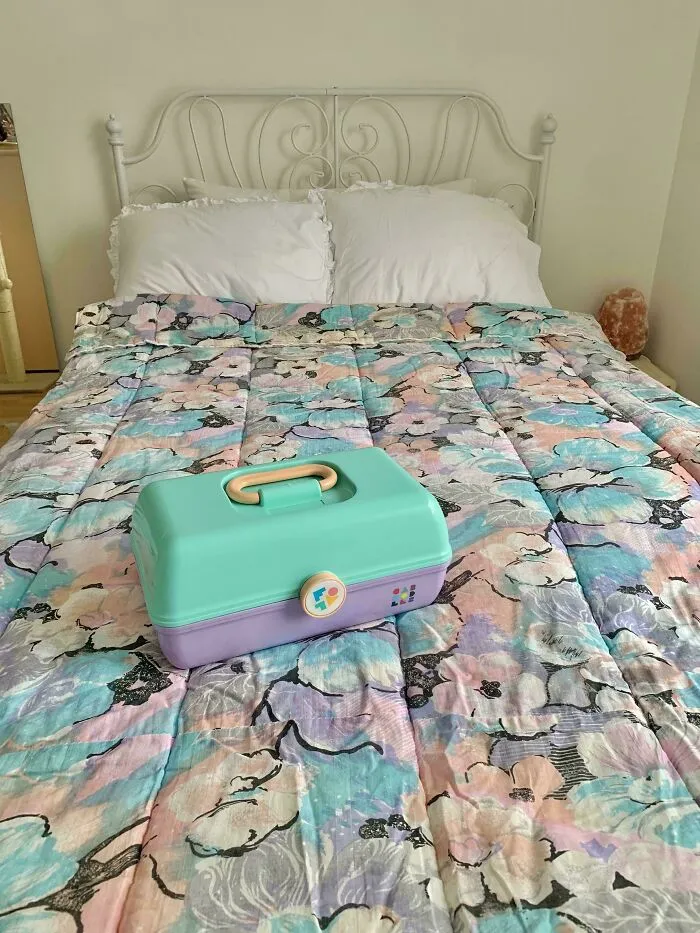 A pastel floral comforter on a bed, with a teal and lavender case, reflecting 1980s interior design aesthetics.