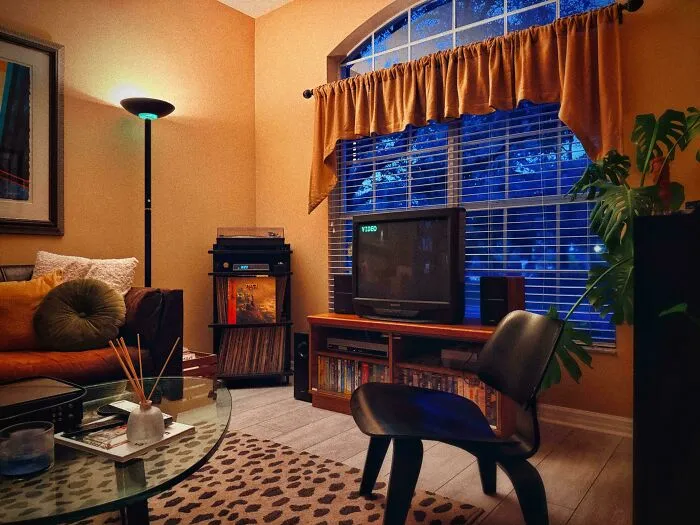 A cozy living room showcasing 1970s and 1980s interior design with a vintage TV, record player, and warm lighting.