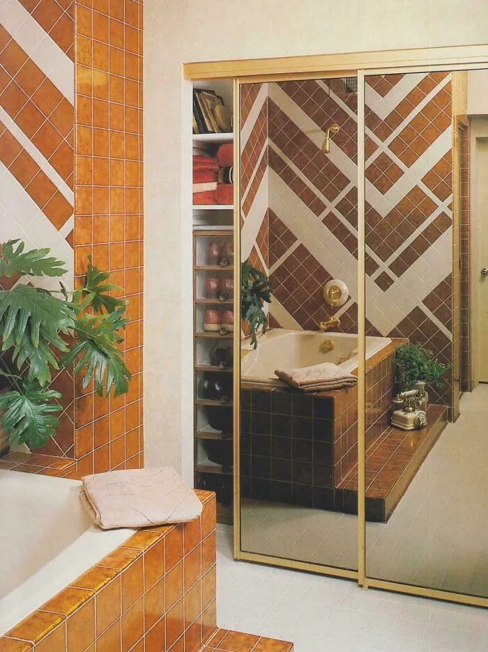 A bathroom with geometric orange and white tiles, showcasing 1970s and 1980s interior design.